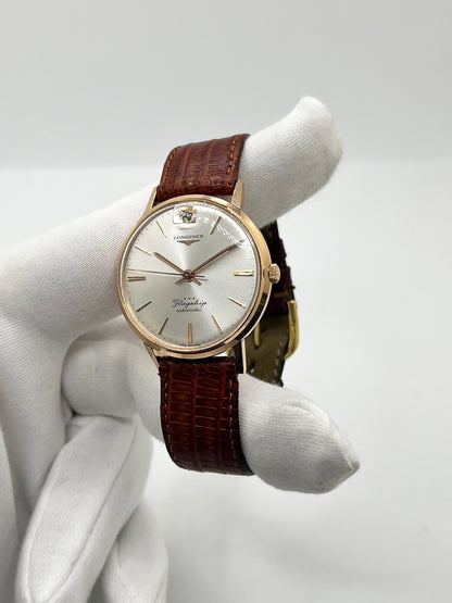 Montre Longines Flagship 2407 vintage en très bon état, datant approximativement de 1962, avec mouvement automatique calibre 341. Son boîtier de 35 mm en or rose est associé à un cadran argent à index bâtons et un verre Plexiglas. Cette Longines Flagship possède un bracelet en cuir de lézard brun avec boucle ardillon en acier. Elle dispose également d’une fonction date et d’un design élégant et intemporel.