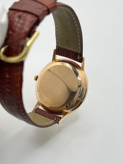 Montre Longines Flagship 2407 vintage en très bon état, datant approximativement de 1962, avec mouvement automatique calibre 341. Son boîtier de 35 mm en or rose est associé à un cadran argent à index bâtons et un verre Plexiglas. Cette Longines Flagship possède un bracelet en cuir de lézard brun avec boucle ardillon en acier. Elle dispose également d’une fonction date et d’un design élégant et intemporel.