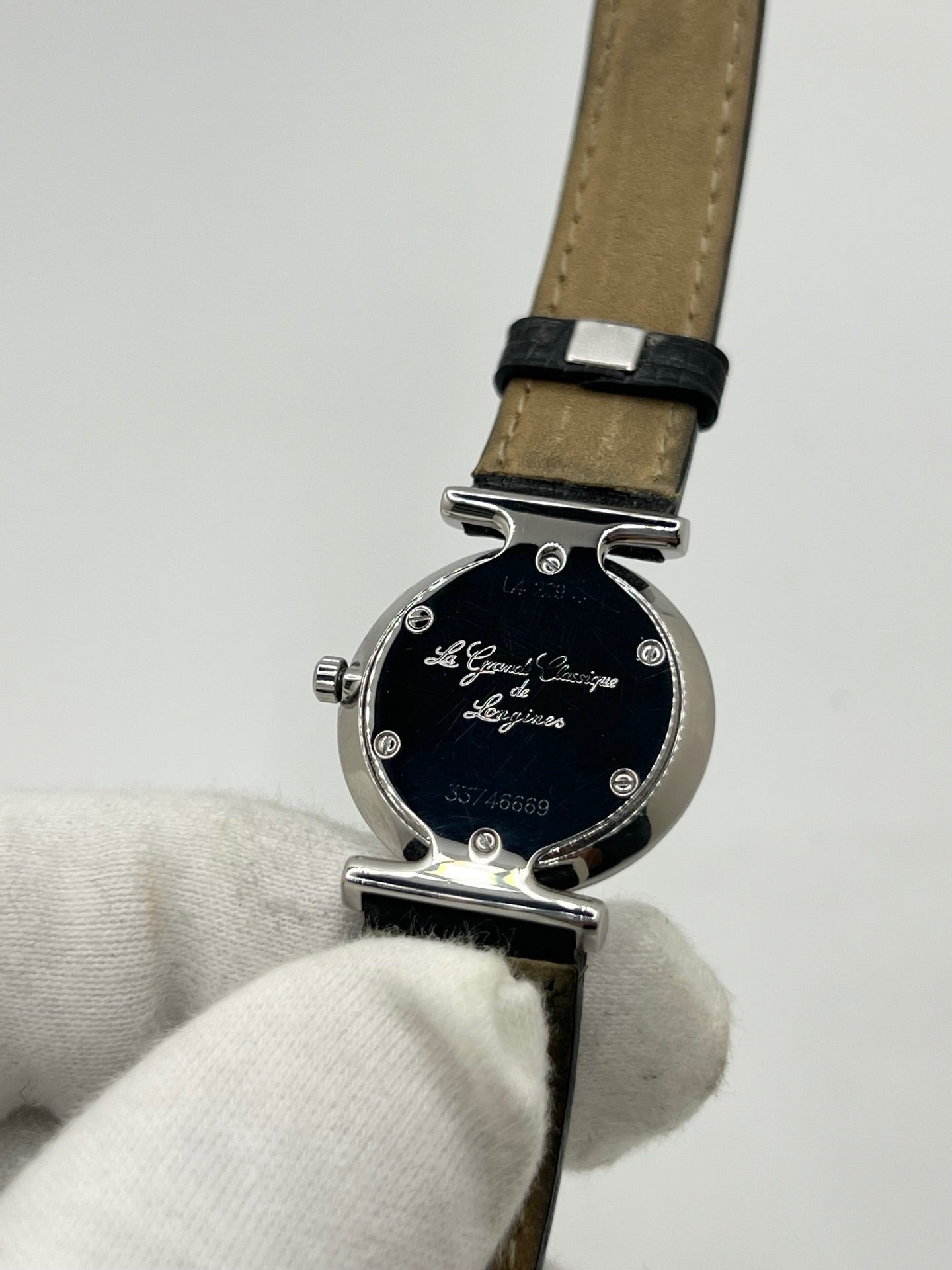Montre Longines La Grande Classique L4.209.4 pour femme en acier avec bracelet en cuir de lézard noir. Ce modèle à mouvement quartz est doté d'un boîtier de 24 mm, d'un cadran blanc épuré sans chiffres, d'une lunette en acier et d'un verre saphir. Élégante et intemporelle, cette montre de luxe d'occasion est en très bon état avec de légères traces d'usure. Son design raffiné en fait un choix idéal pour un usage quotidien ou une collection horlogère.