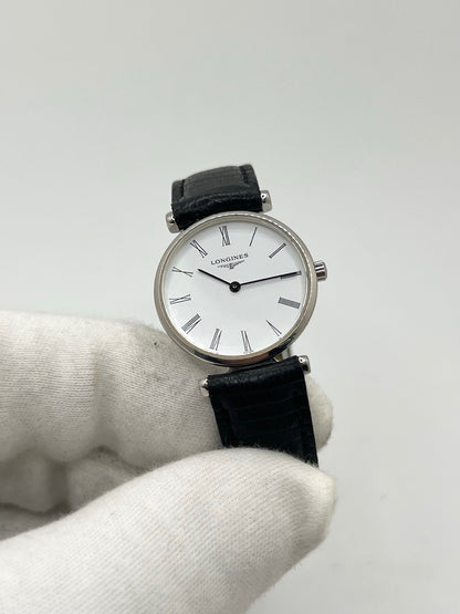 Montre Longines La Grande Classique L4.209.4 pour femme en acier avec bracelet en cuir de lézard noir. Ce modèle à mouvement quartz est doté d'un boîtier de 24 mm, d'un cadran blanc épuré sans chiffres, d'une lunette en acier et d'un verre saphir. Élégante et intemporelle, cette montre de luxe d'occasion est en très bon état avec de légères traces d'usure. Son design raffiné en fait un choix idéal pour un usage quotidien ou une collection horlogère.