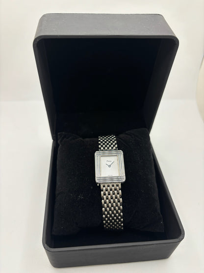 Montre Poiray Ma Première pour femme en acier inoxydable avec boîtier rectangulaire de 22,5 x 26 mm. Cette montre quartz arbore un cadran argenté protégé par un verre saphir et un bracelet en acier à boucle double pliant. Élégante et intemporelle, cette montre de luxe féminine d'occasion séduit par son design emblématique et sa finition raffinée. Modèle iconique de la maison Poiray, idéal pour les amateurs d'horlogerie et de joaillerie française.
