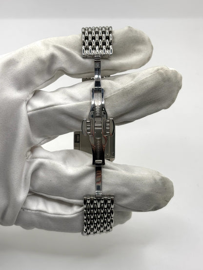 Montre Poiray Ma Première pour femme en acier inoxydable avec boîtier rectangulaire de 22,5 x 26 mm. Cette montre quartz arbore un cadran argenté protégé par un verre saphir et un bracelet en acier à boucle double pliant. Élégante et intemporelle, cette montre de luxe féminine d'occasion séduit par son design emblématique et sa finition raffinée. Modèle iconique de la maison Poiray, idéal pour les amateurs d'horlogerie et de joaillerie française.
