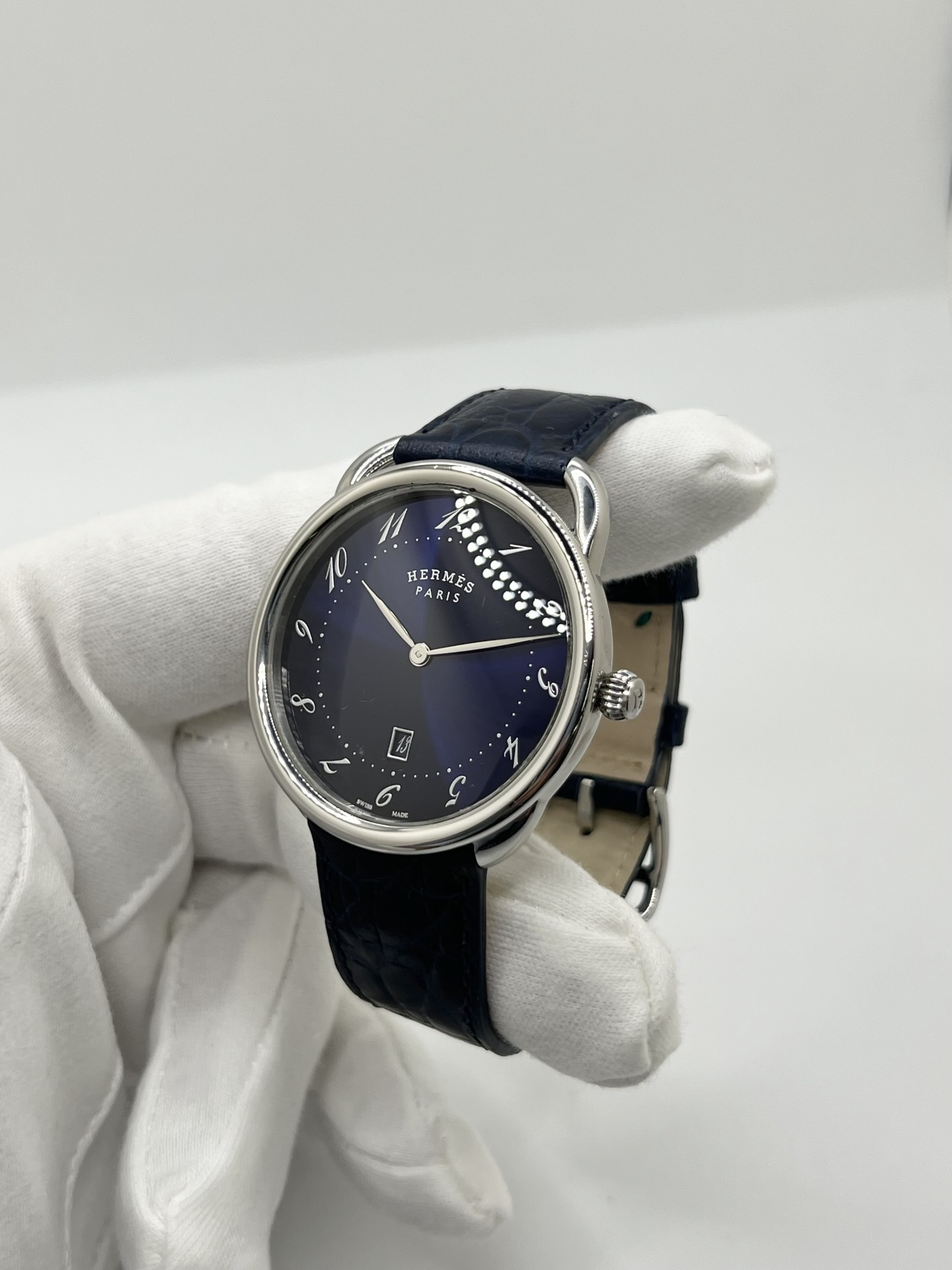 Montre Hermès Arceau grand modèle AR7Q.810 en acier avec cadran blanc épuré, chiffres arabes inclinés signature de la collection Arceau, mouvement quartz précis et bracelet en cuir élégant. Design intemporel et raffiné, idéal pour une tenue chic au quotidien ou une occasion spéciale, alliant savoir-faire horloger et esthétique minimaliste.