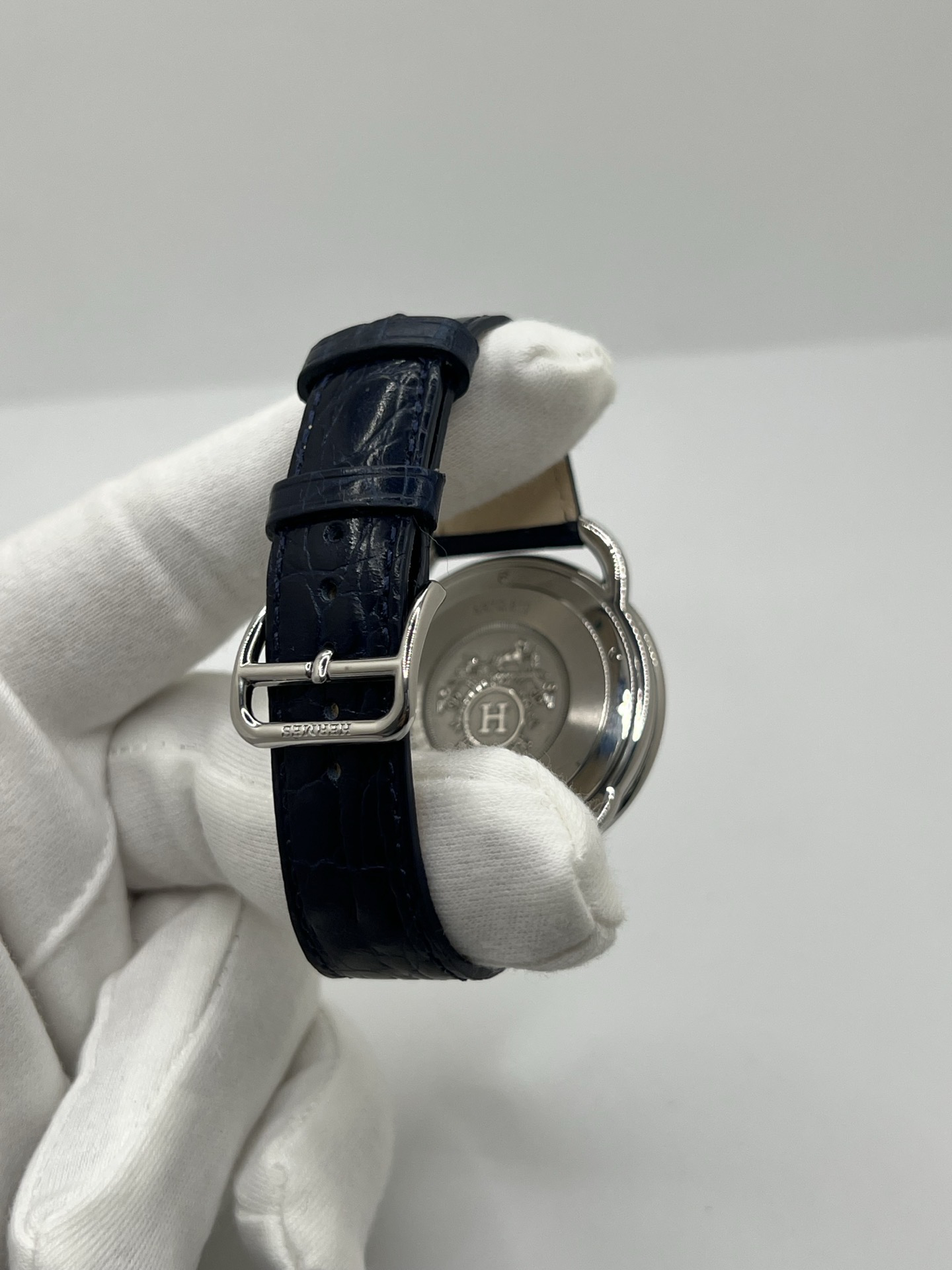 Montre Hermès Arceau grand modèle AR7Q.810 en acier avec cadran blanc épuré, chiffres arabes inclinés signature de la collection Arceau, mouvement quartz précis et bracelet en cuir élégant. Design intemporel et raffiné, idéal pour une tenue chic au quotidien ou une occasion spéciale, alliant savoir-faire horloger et esthétique minimaliste.