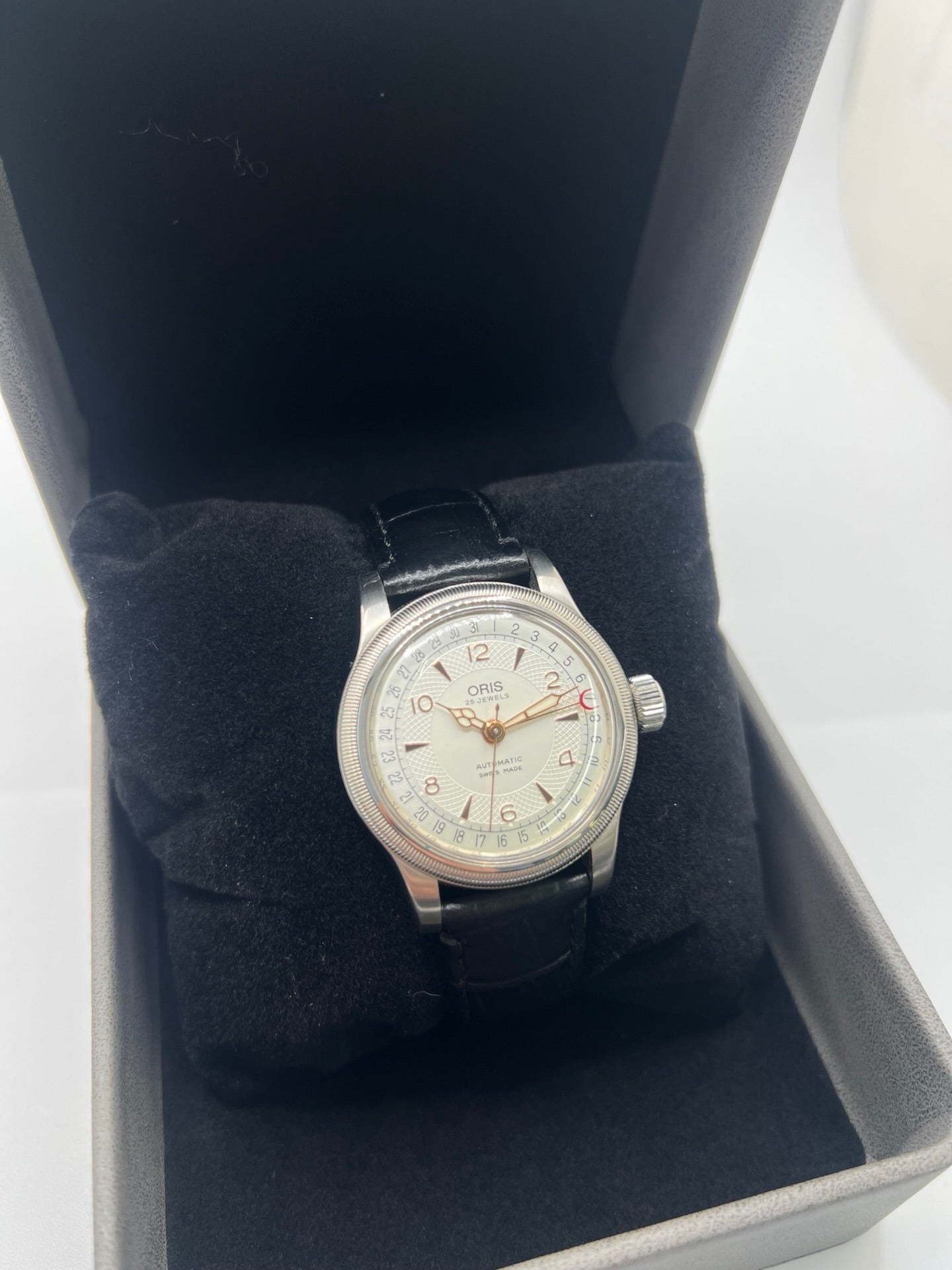 Montre mécanique automatique pour homme au style vintage, dotée d’un boîtier en acier de 36 mm et d’un cadran argent à chiffres arabes lisibles. Modèle équipé d’une fonction date par aiguille centrale, verre en matière plastique et lunette en acier. Bracelet noir avec boucle ardillon en acier. Montre d’occasion en très bon état, présentant de légères traces d’usure superficielles, récemment révisée, idéale pour les amateurs d’horlogerie classique.