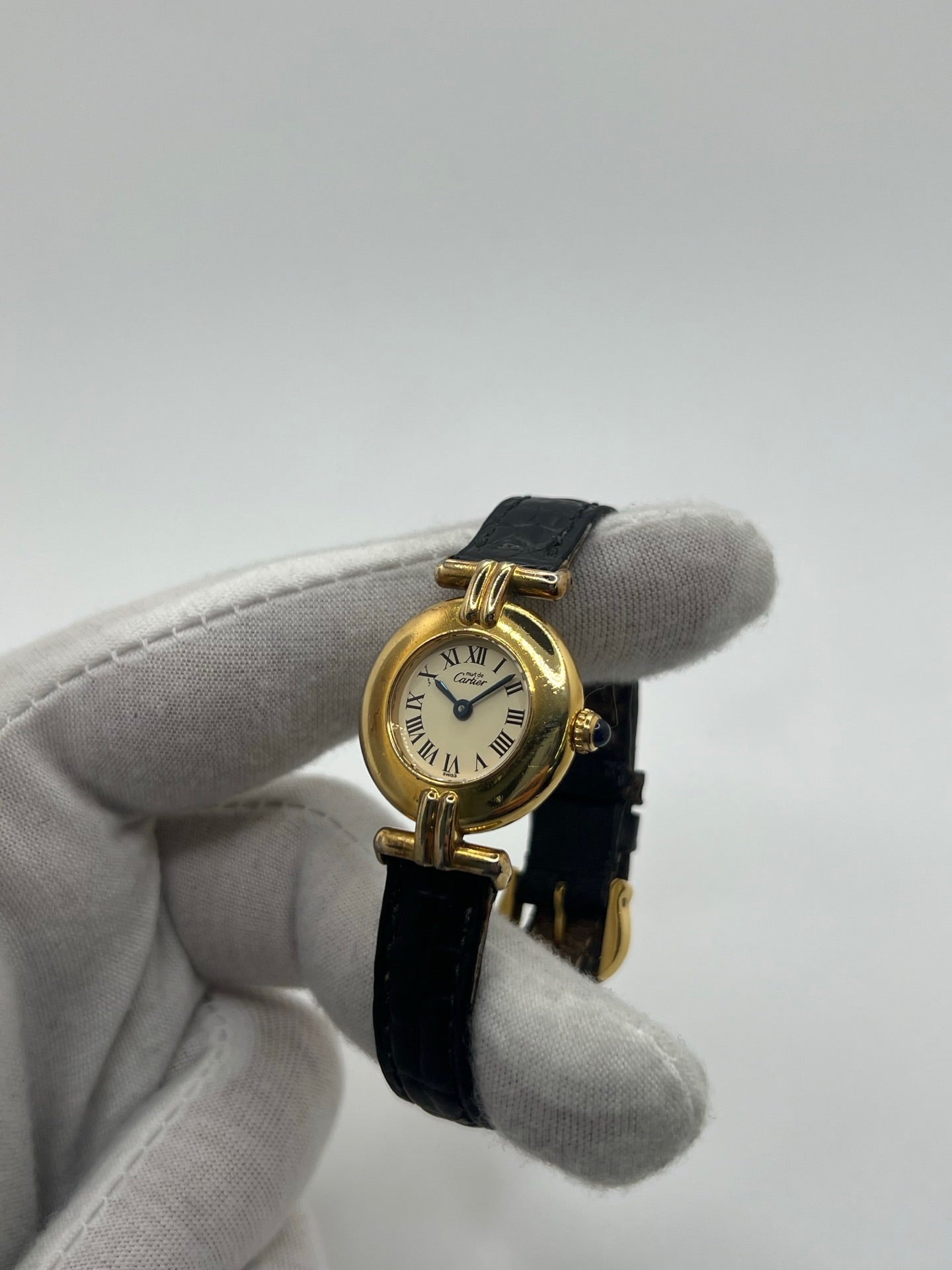 Montre Cartier Colisée Must Vermeil réf. 590002 pour femme, équipée d’un mouvement quartz précis. Boîtier en argent vermeil de 24 mm, cadran blanc à chiffres romains, verre saphir et bracelet en cuir noir avec boucle ardillon. Modèle d’occasion en bon état présentant quelques traces d’usure. Idéal pour les amateurs de montres élégantes et intemporelles.