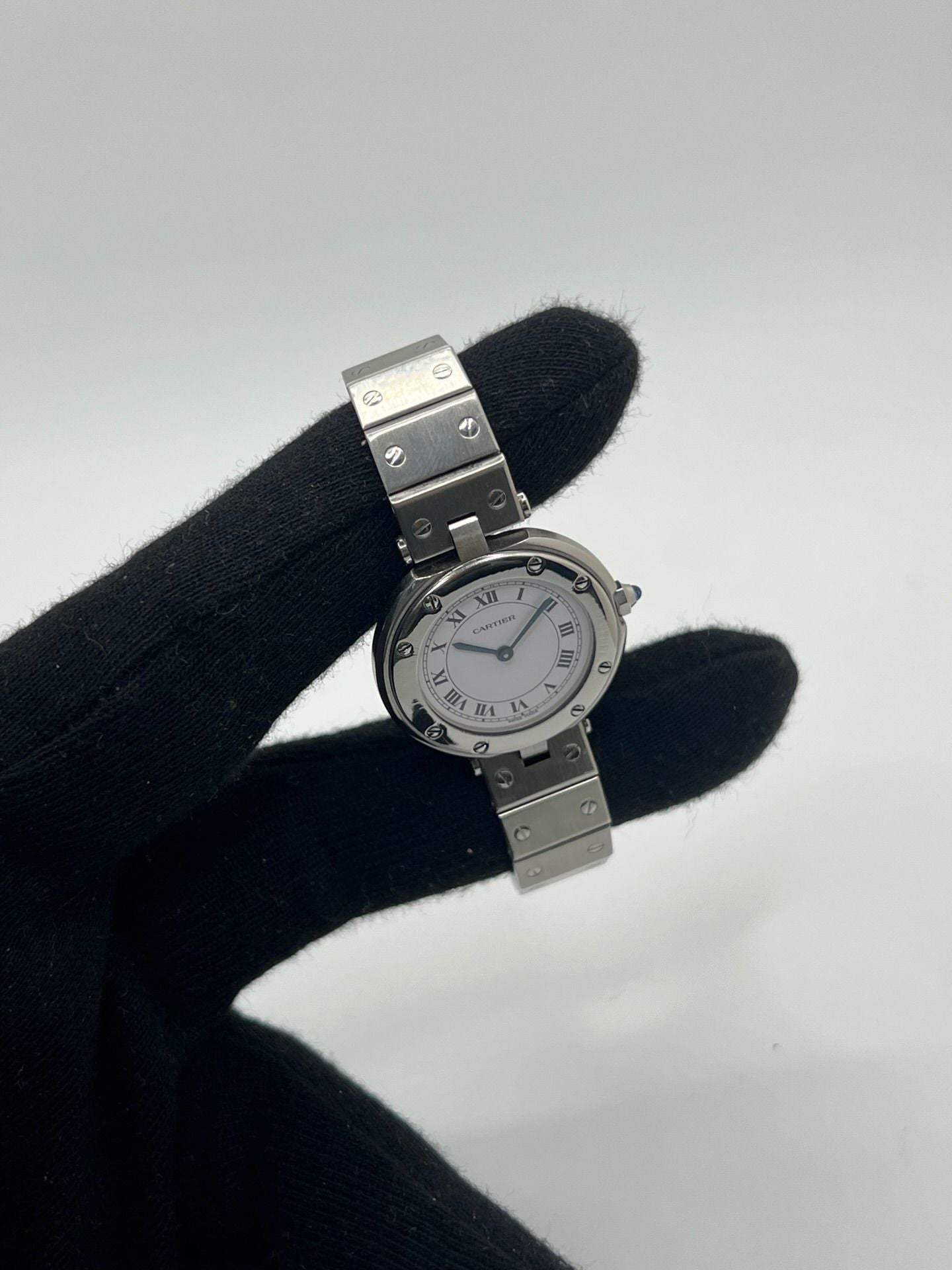 Montre Cartier Santos Vendôme référence 8192 en acier, modèle pour femme avec boîtier rond de 27 mm, cadran blanc à chiffres romains et mouvement quartz. Bracelet acier assorti, boucle à plis et verre saphir. Montre vintage de 1981 en très bon état, livrée avec coffret et papiers d’origine.