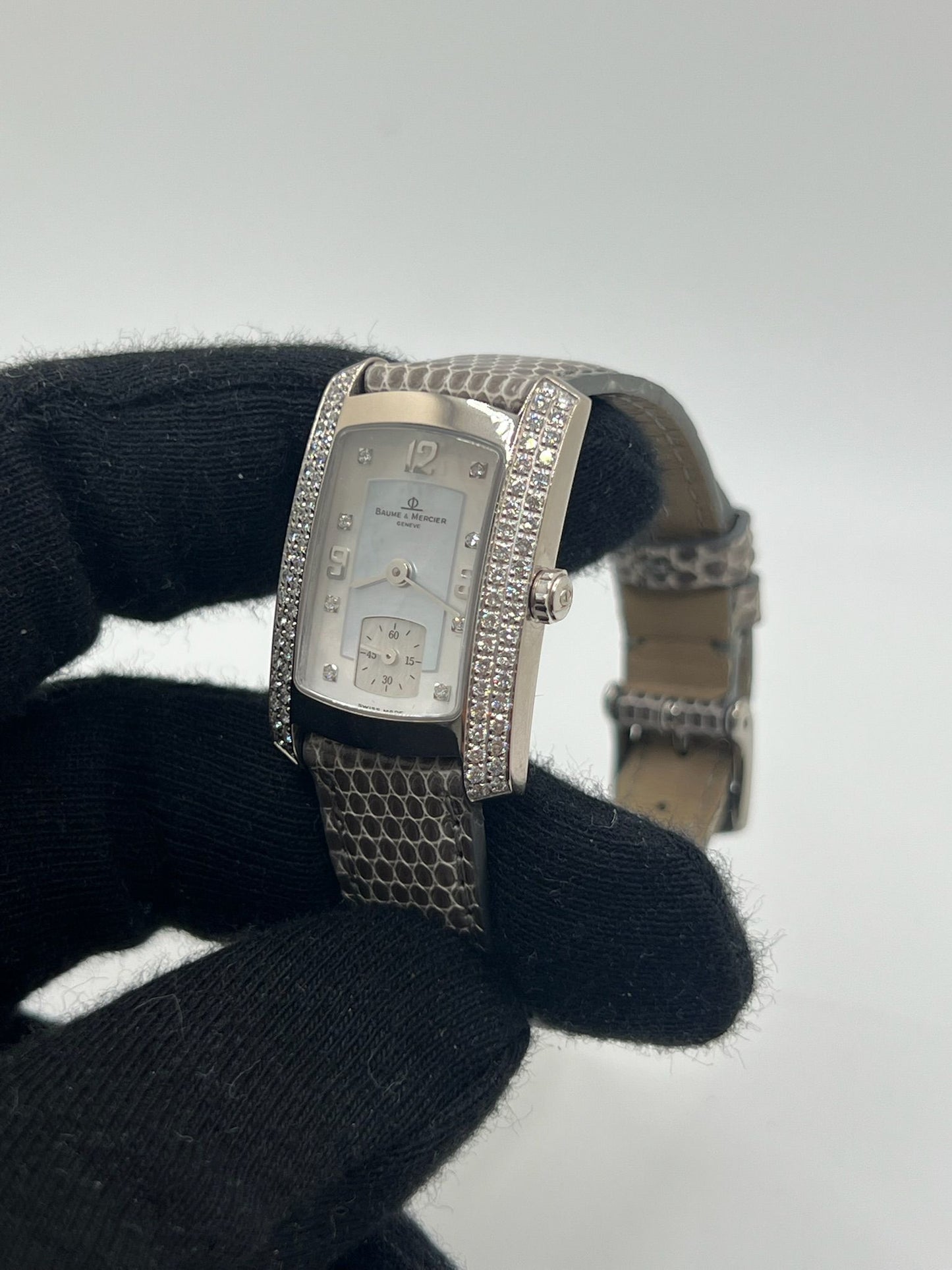 Cette Baume & Mercier Hampton Milleis incarne l’élégance intemporelle avec son boîtier rectangulaire en or blanc 18K, sublimé de diamants. Son cadran aux lignes Art déco reflète l’excellence horlogère suisse. Montée sur un bracelet en cuir de lézard (non d’origine), elle est livrée avec son coffret d’origine. Entièrement révisée en juin 2025 et garantie un an, cette pièce rare allie luxe, raffinement et fiabilité, parfaite pour les passionnés de belles montres.