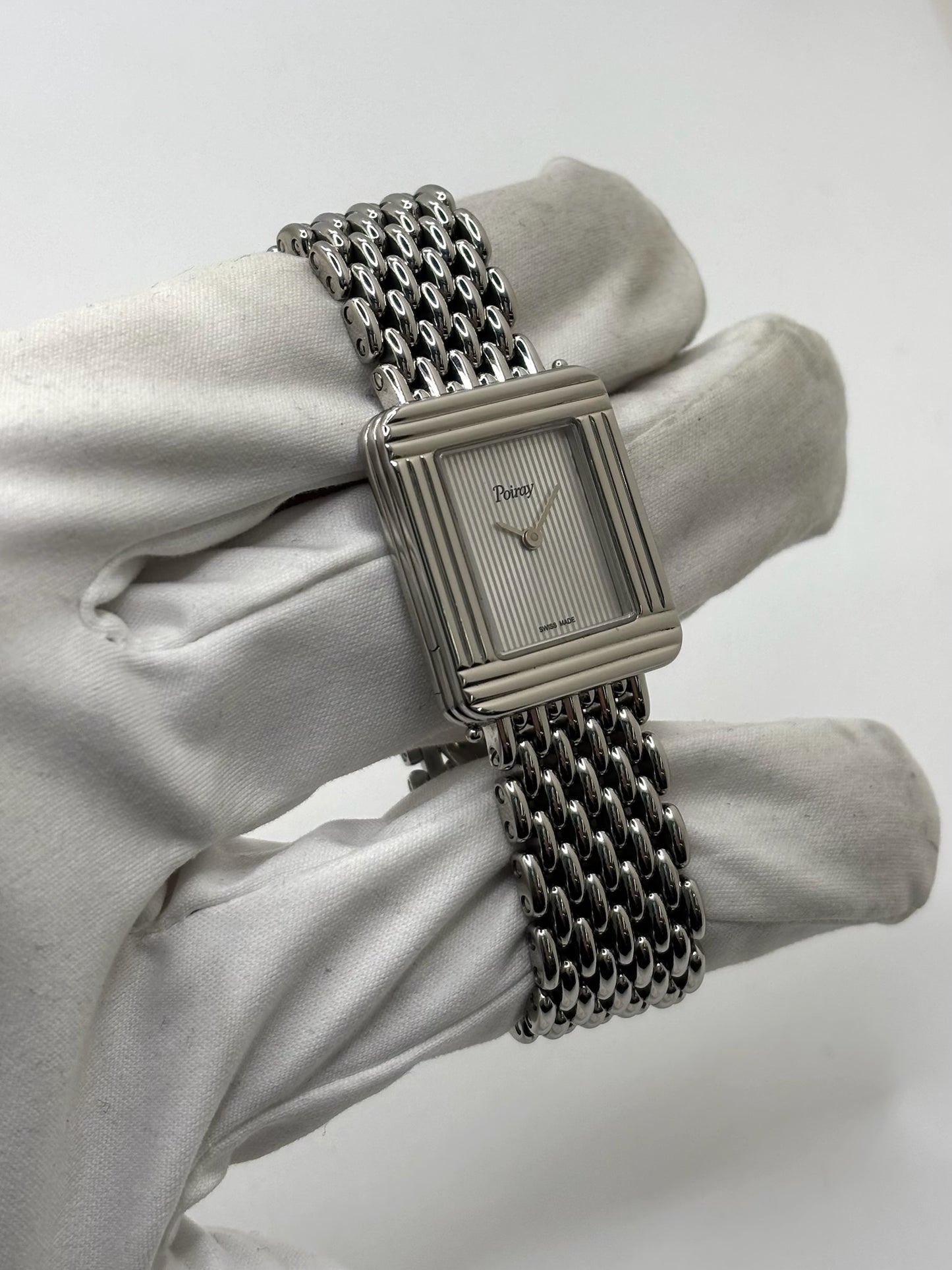 Montre Poiray Ma Première pour femme en acier inoxydable avec boîtier rectangulaire de 22,5 x 26 mm. Cette montre quartz arbore un cadran argenté protégé par un verre saphir et un bracelet en acier à boucle double pliant. Élégante et intemporelle, cette montre de luxe féminine d'occasion séduit par son design emblématique et sa finition raffinée. Modèle iconique de la maison Poiray, idéal pour les amateurs d'horlogerie et de joaillerie française.
