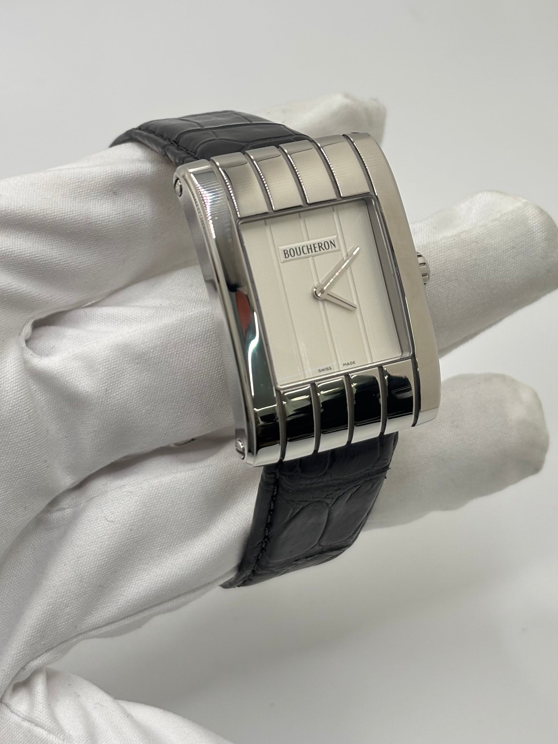 Montre Boucheron Reflet Icare Parallèle en acier, équipée d’un mouvement quartz précis. Boîtier rectangulaire 28 x 40 mm avec verre saphir et cadran blanc épuré. Bracelet en cuir de crocodile noir avec boucle ardillon en acier. Modèle homme/unisexe au design élégant et intemporel. Montre d’occasion en très bon état, présentant de légères traces d’usure non perceptibles au toucher, révisée en avril 2026, idéale pour amateurs d’horlogerie et de pièces de luxe.
