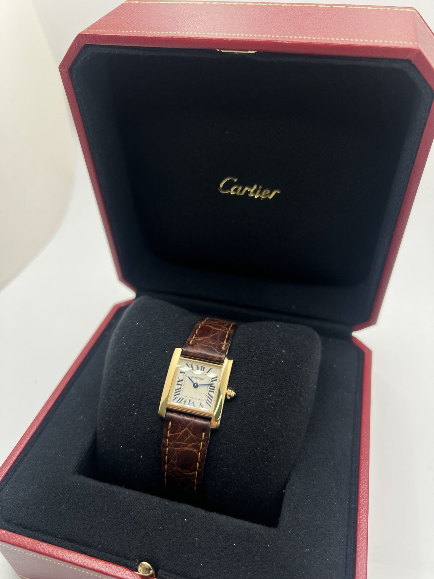 Montre Cartier Tank Française référence 1820 en or jaune 18K, petit modèle pour femme, boîtier rectangulaire emblématique aux lignes droites et élégantes, cadran blanc avec chiffres romains noirs, minuterie chemin de fer et aiguilles bleuies en forme de glaive. Bracelet intégré en acier avec boucle déployante. Mouvement quartz précis. Montre de luxe intemporelle, raffinée et iconique, idéale pour un porté quotidien ou une tenue habillée.