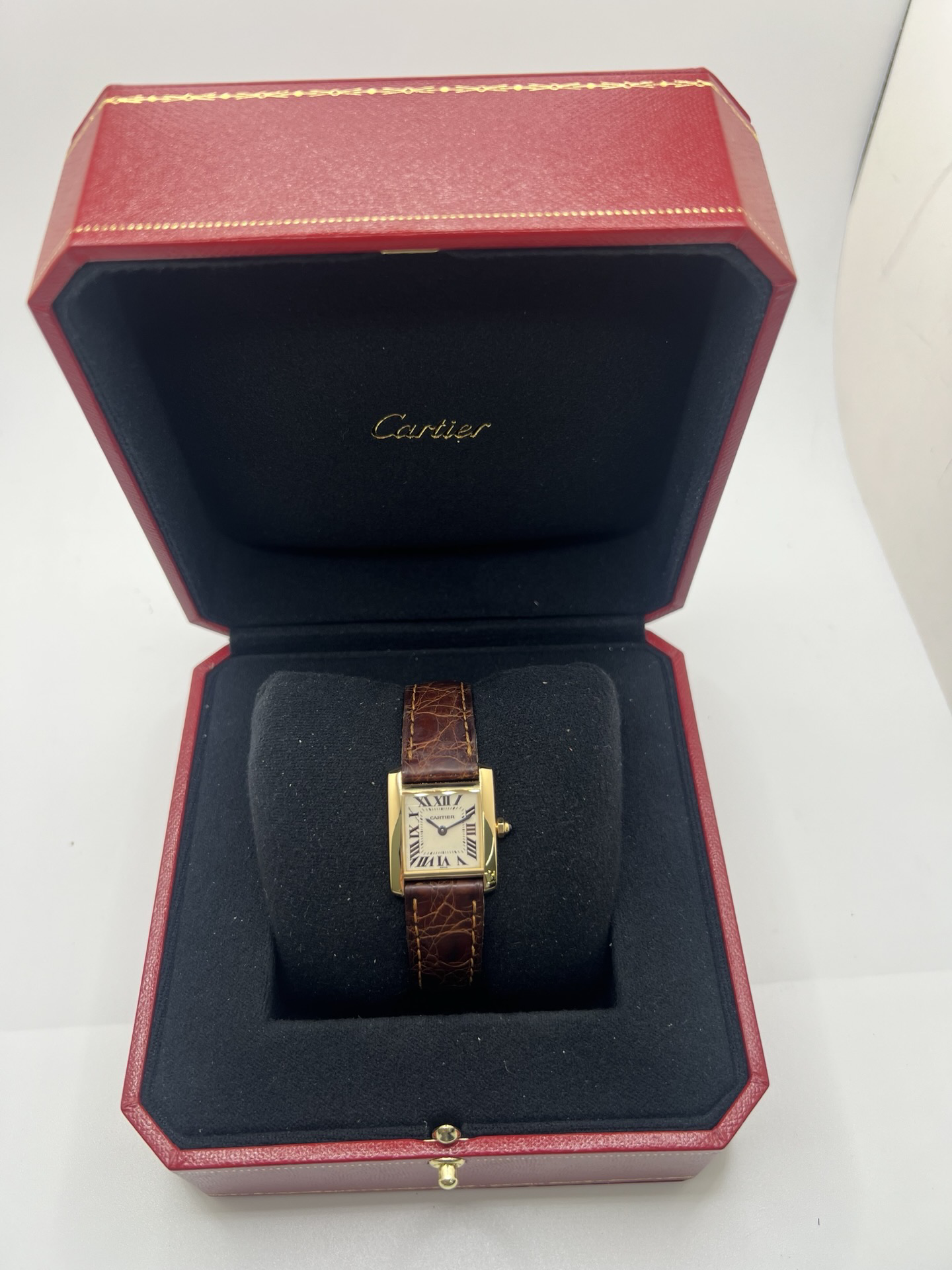 Montre Cartier Tank Française référence 1820 en or jaune 18K, petit modèle pour femme, boîtier rectangulaire emblématique aux lignes droites et élégantes, cadran blanc avec chiffres romains noirs, minuterie chemin de fer et aiguilles bleuies en forme de glaive. Bracelet intégré en acier avec boucle déployante. Mouvement quartz précis. Montre de luxe intemporelle, raffinée et iconique, idéale pour un porté quotidien ou une tenue habillée.