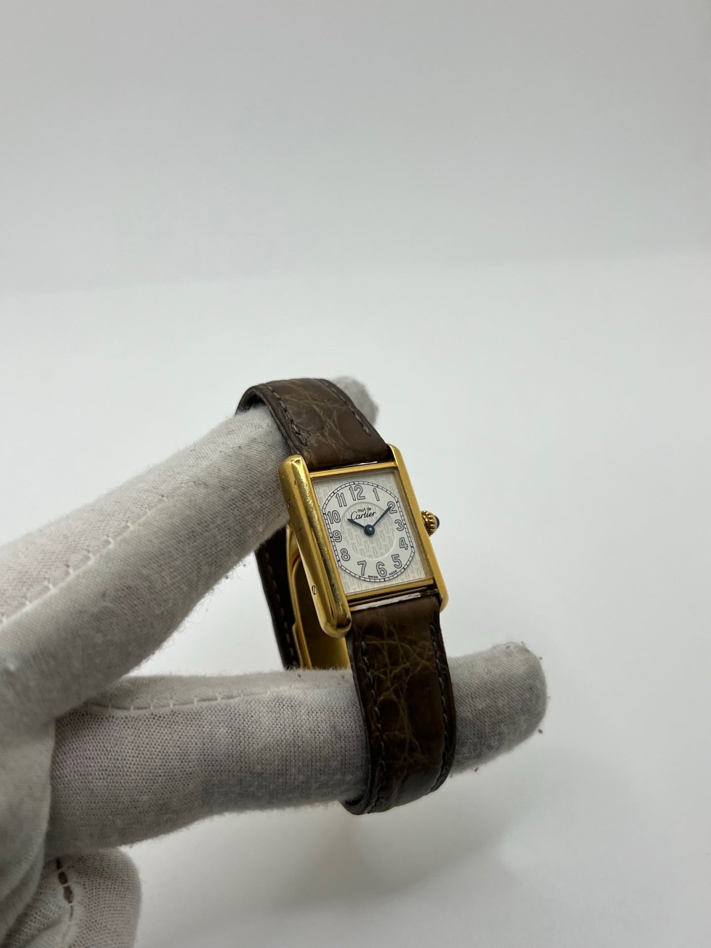 Montre Cartier Tank Vermeil 2415 pour femme, équipée d’un mouvement quartz et d’un boîtier en argent de 22 x 29 mm. Ce modèle d’occasion en bon état présente des traces d’usure visibles, un cadran blanc à chiffres arabes, un verre minéral et un bracelet en cuir brun avec boucle ardillon en argent. Élégante et classique, la Cartier Tank Vermeil 2415 séduit par son design intemporel, idéale pour les passionnées de montres de luxe.