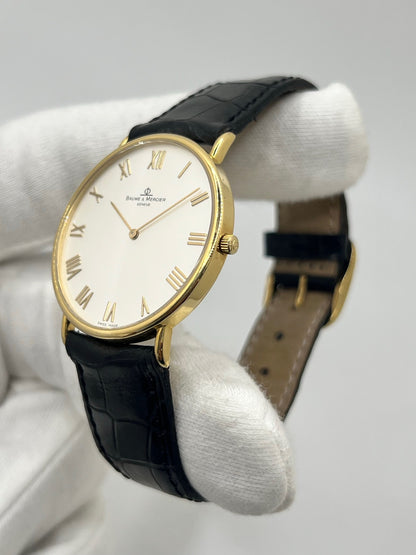 Montre Baume & Mercier Classima 15172A en or jaune, équipée d’un mouvement à quartz et d’un boîtier de 33 mm. Son cadran blanc à chiffres romains apporte une allure élégante et intemporelle, tandis que le verre saphir assure sa protection. Ce modèle est monté sur un bracelet noir en cuir de crocodile avec boucle ardillon en acier. Une montre raffinée, idéale pour une tenue chic et élégante, en très bon état.