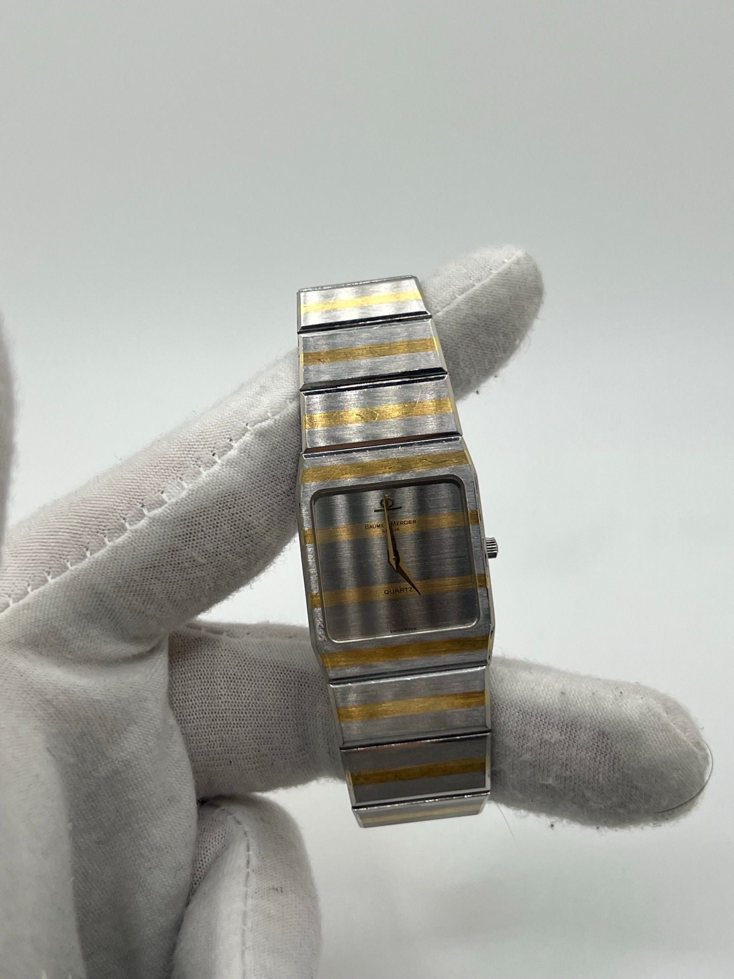 Montre Baume & Mercier Carlo Zebra 5739.038 pour homme/unisexe, mouvement quartz, boîtier acier 25x32 mm, cadran or, verre saphir et bracelet or/acier avec boucle pli. Étanche 10 ATM, d'occasion en bon état, disponible sans coffret ni papiers d'origine. Idéale pour les amateurs de montres de luxe élégantes et intemporelles.