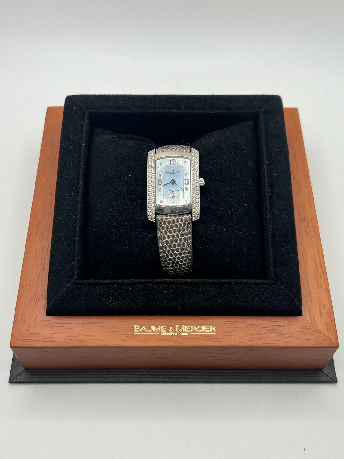 Cette Baume & Mercier Hampton Milleis incarne l’élégance intemporelle avec son boîtier rectangulaire en or blanc 18K, sublimé de diamants. Son cadran aux lignes Art déco reflète l’excellence horlogère suisse. Montée sur un bracelet en cuir de lézard (non d’origine), elle est livrée avec son coffret d’origine. Entièrement révisée en juin 2025 et garantie un an, cette pièce rare allie luxe, raffinement et fiabilité, parfaite pour les passionnés de belles montres.
