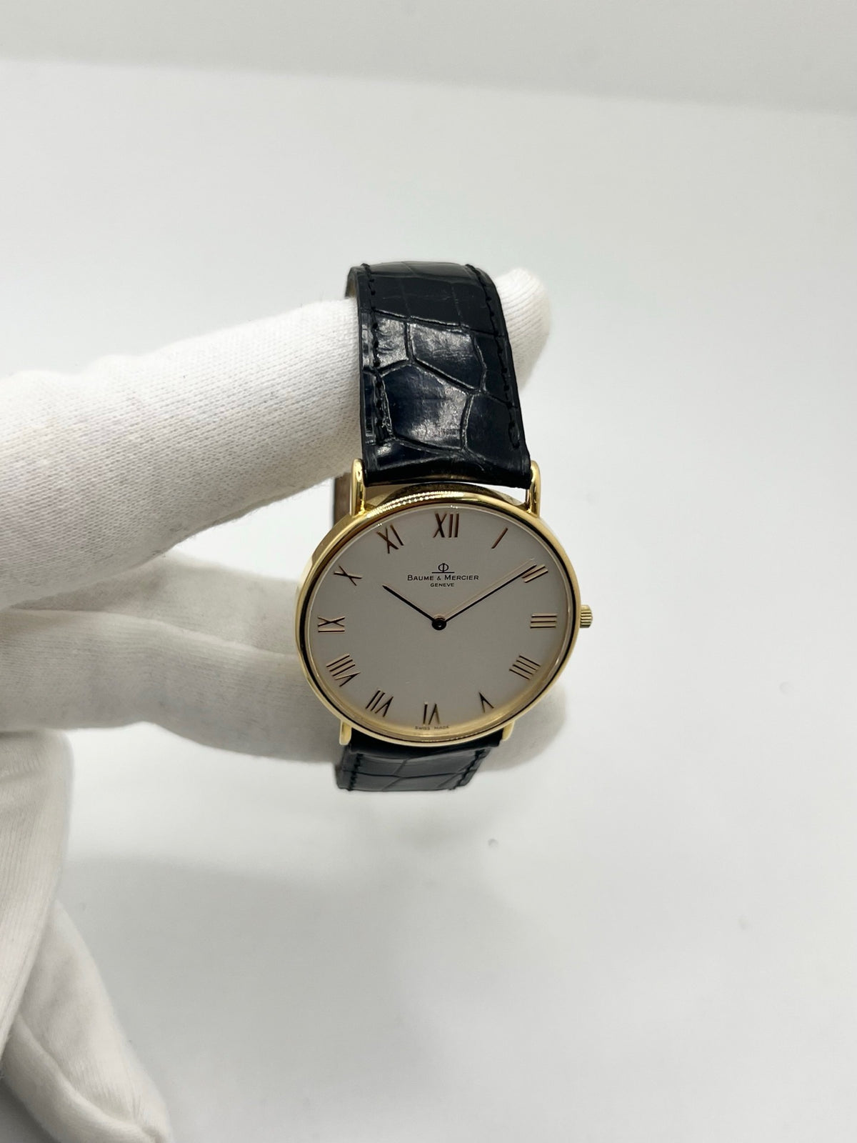 Montre Baume & Mercier Classima 15172A en or jaune, équipée d’un mouvement à quartz et d’un boîtier de 33 mm. Son cadran blanc à chiffres romains apporte une allure élégante et intemporelle, tandis que le verre saphir assure sa protection. Ce modèle est monté sur un bracelet noir en cuir de crocodile avec boucle ardillon en acier. Une montre raffinée, idéale pour une tenue chic et élégante, en très bon état.