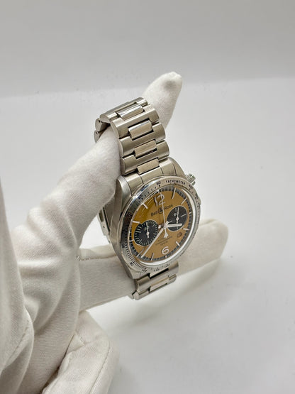 Montre Bell & Ross BR V2 Chronograph Heritage référence BRV2-94-S équipée d'un mouvement automatique. Son boîtier en acier de 41 mm est associé à un bracelet en acier argenté avec boucle déployante double plis. Le cadran doré à chiffres arabes est protégé par un verre minéral et intègre les fonctions chronographe et date. Cette montre d'occasion, révisée en interne et proposée en très bon état, allie esprit aviation, design vintage et précision horlogère suisse.