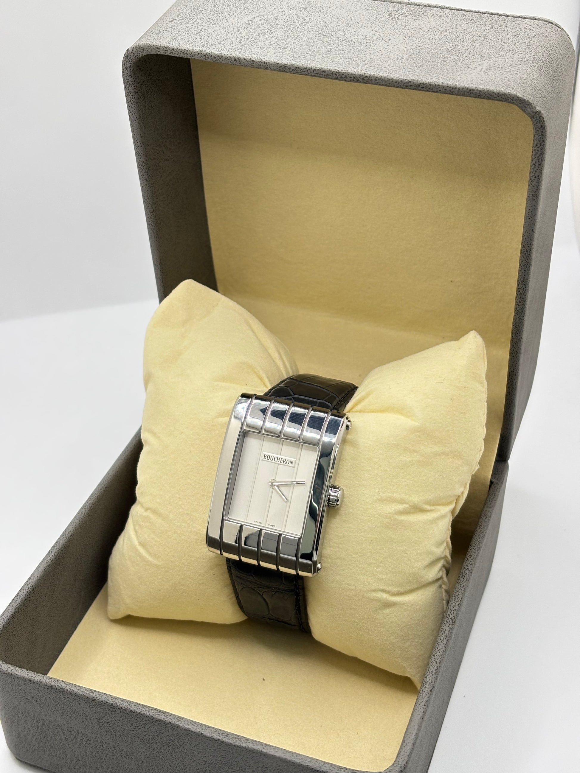 Montre Boucheron Reflet Icare Parallèle en acier, équipée d’un mouvement quartz précis. Boîtier rectangulaire 28 x 40 mm avec verre saphir et cadran blanc épuré. Bracelet en cuir de crocodile noir avec boucle ardillon en acier. Modèle homme/unisexe au design élégant et intemporel. Montre d’occasion en très bon état, présentant de légères traces d’usure non perceptibles au toucher, révisée en avril 2026, idéale pour amateurs d’horlogerie et de pièces de luxe.