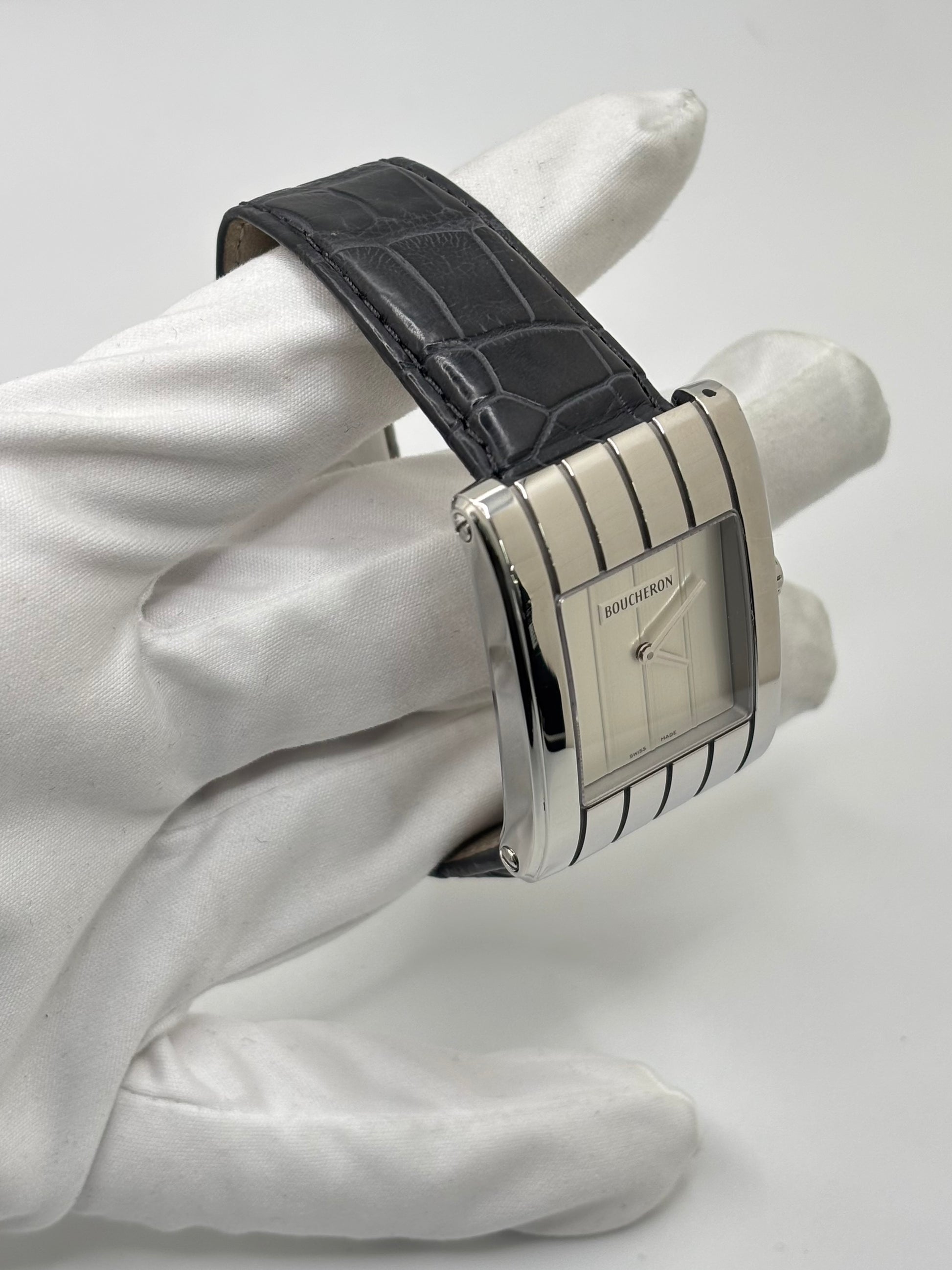 Montre Boucheron Reflet Icare Parallèle en acier, équipée d’un mouvement quartz précis. Boîtier rectangulaire 28 x 40 mm avec verre saphir et cadran blanc épuré. Bracelet en cuir de crocodile noir avec boucle ardillon en acier. Modèle homme/unisexe au design élégant et intemporel. Montre d’occasion en très bon état, présentant de légères traces d’usure non perceptibles au toucher, révisée en avril 2026, idéale pour amateurs d’horlogerie et de pièces de luxe.