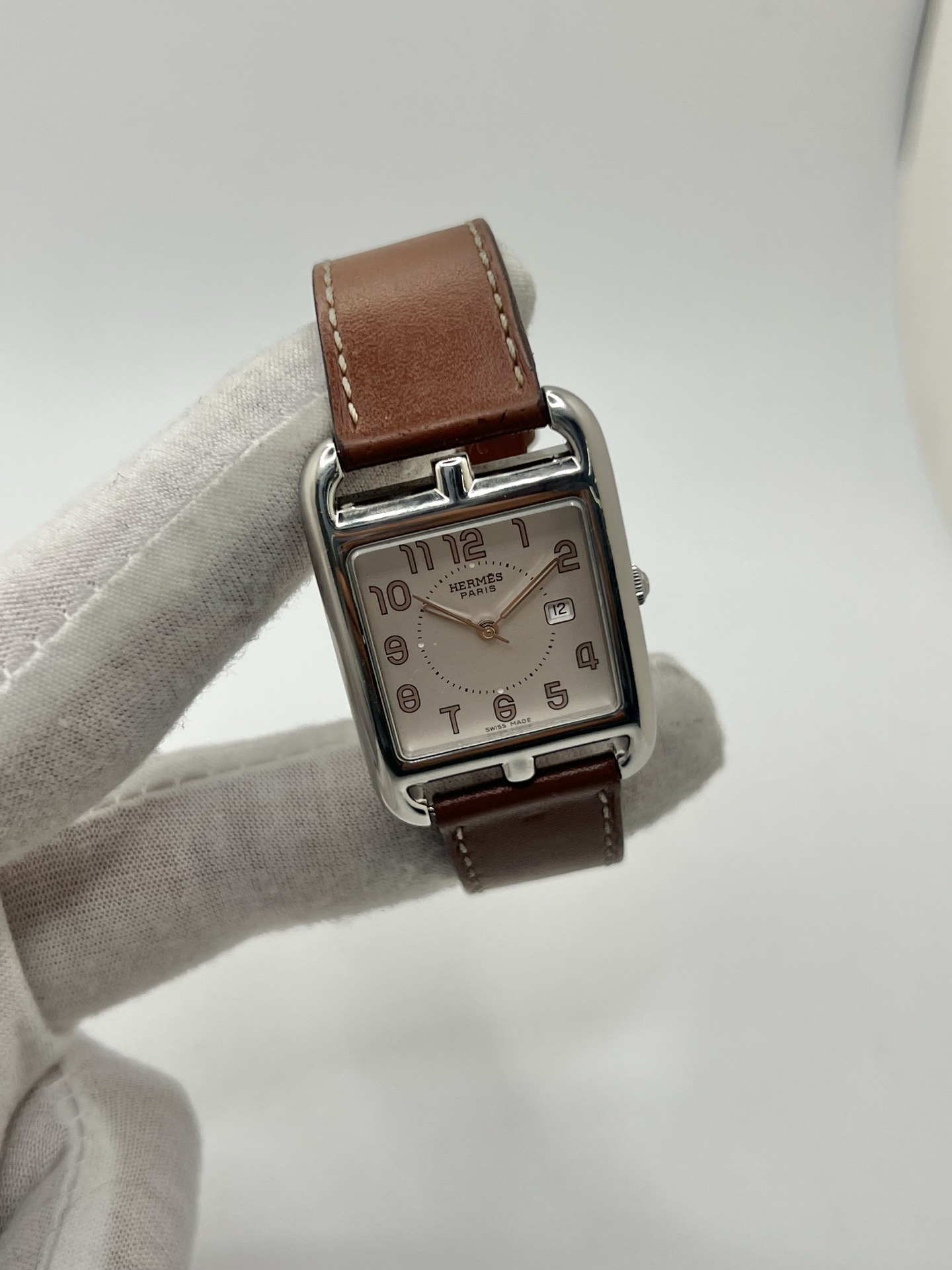 Montre Hermès Cape Cod Grand Modèle en acier inoxydable, boîtier rectangulaire iconique aux lignes élégantes et contemporaines, cadran argenté épuré avec chiffres arabes stylisés et aiguilles fines. Bracelet en cuir signature Hermès offrant confort et raffinement. Mouvement quartz précis. Montre de luxe intemporelle et sophistiquée, idéale pour un porté quotidien ou une tenue habillée, symbole du savoir-faire horloger et du style parisien.