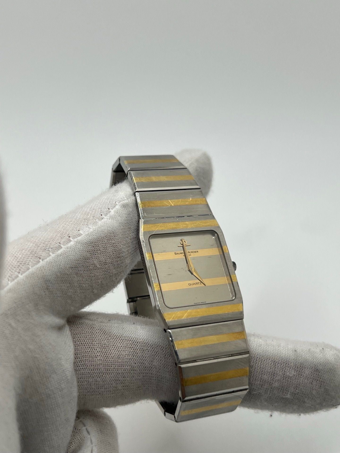 Montre Baume & Mercier Carlo Zebra 5739.038 pour homme/unisexe, mouvement quartz, boîtier acier 25x32 mm, cadran or, verre saphir et bracelet or/acier avec boucle pli. Étanche 10 ATM, d'occasion en bon état, disponible sans coffret ni papiers d'origine. Idéale pour les amateurs de montres de luxe élégantes et intemporelles.