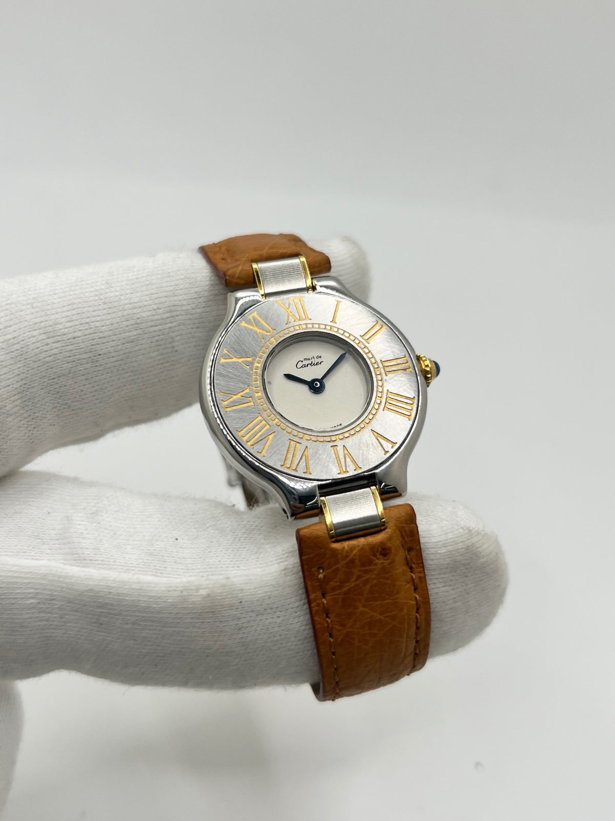 Montre Cartier 21 Must de Cartier 9011 pour femme, équipée d’un mouvement quartz et d’un boîtier en acier de 28 mm. Son cadran blanc offre une esthétique élégante et intemporelle. Cette montre Cartier est montée sur un bracelet brun en cuir avec boucle déployante à plis. En bon état, elle présente des traces d’usure visibles et perceptibles, notamment quelques rayures, éraflures et petites bosses. Révisée en interne en septembre 2026.
