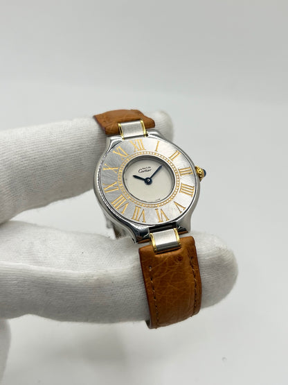 Montre Cartier 21 Must de Cartier 9011 pour femme, équipée d’un mouvement quartz et d’un boîtier en acier de 28 mm. Son cadran blanc offre une esthétique élégante et intemporelle. Cette montre Cartier est montée sur un bracelet brun en cuir avec boucle déployante à plis. En bon état, elle présente des traces d’usure visibles et perceptibles, notamment quelques rayures, éraflures et petites bosses. Révisée en interne en septembre 2026.
