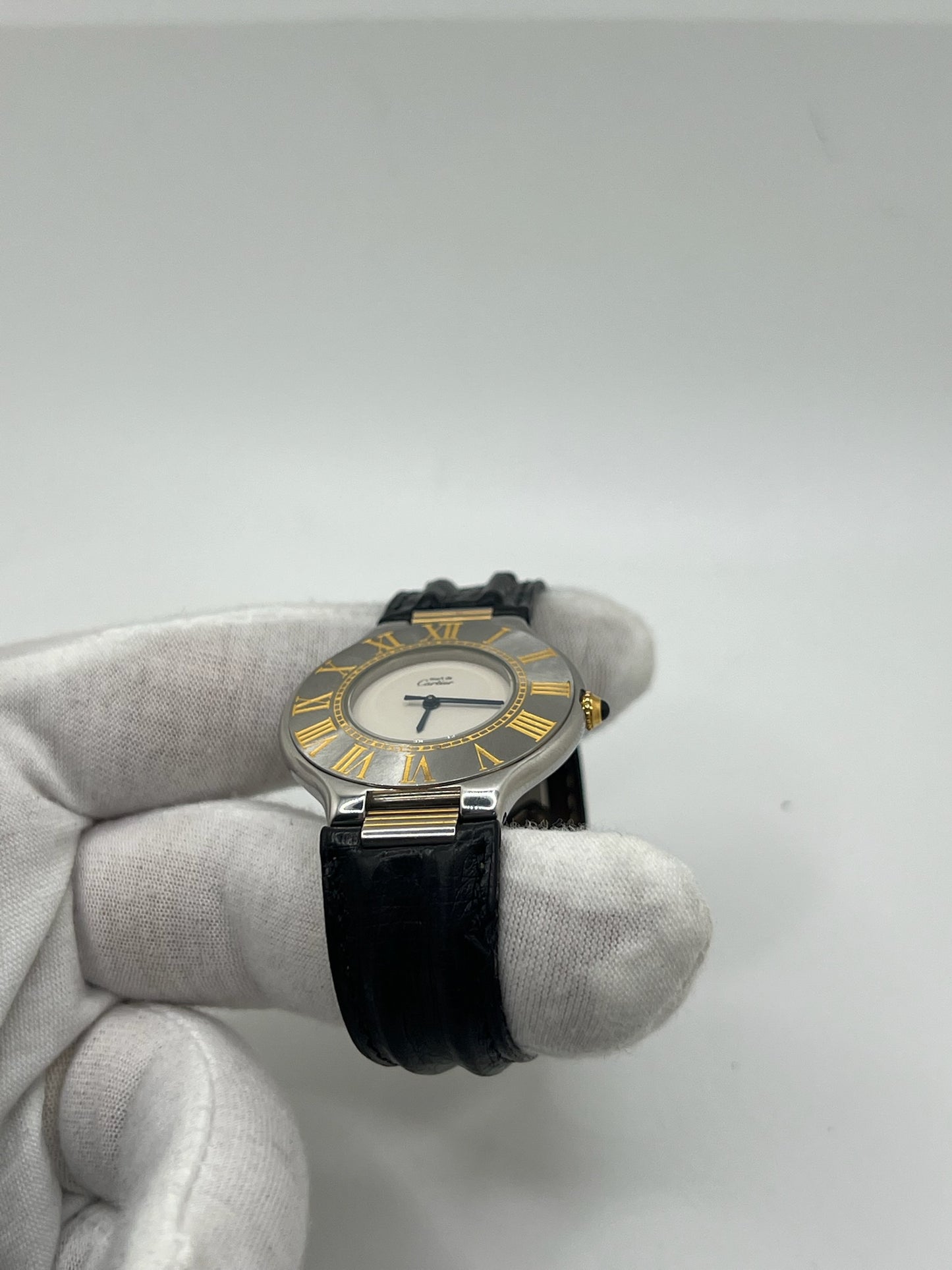 Montre Cartier 21 Must de Cartier avec boîtier 35 mm en or et acier, cadran blanc à chiffres romains, mouvement quartz. Modèle élégant et mixte, équipé d’une boucle déployante sur bracelet cuir noir. Montre de luxe vintage en très bon état, révisée, disponible sans boîte ni papiers d’origine. Idéale pour collectionneur ou amateur de montres emblématiques signées Cartier.