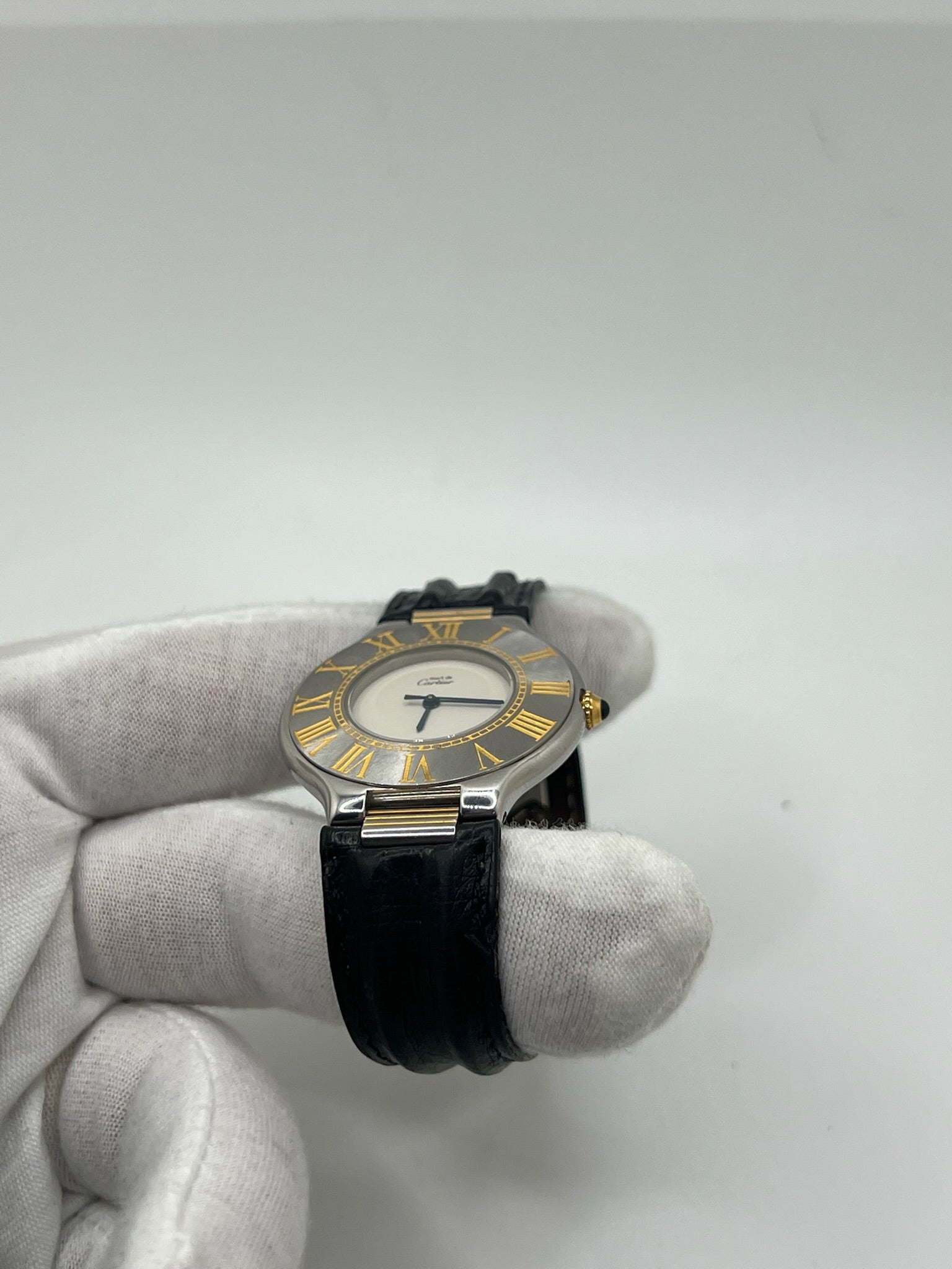 Montre Cartier 21 Must de Cartier avec boîtier 35 mm en or et acier, cadran blanc à chiffres romains, mouvement quartz. Modèle élégant et mixte, équipé d’une boucle déployante sur bracelet cuir noir. Montre de luxe vintage en très bon état, révisée, disponible sans boîte ni papiers d’origine. Idéale pour collectionneur ou amateur de montres emblématiques signées Cartier.