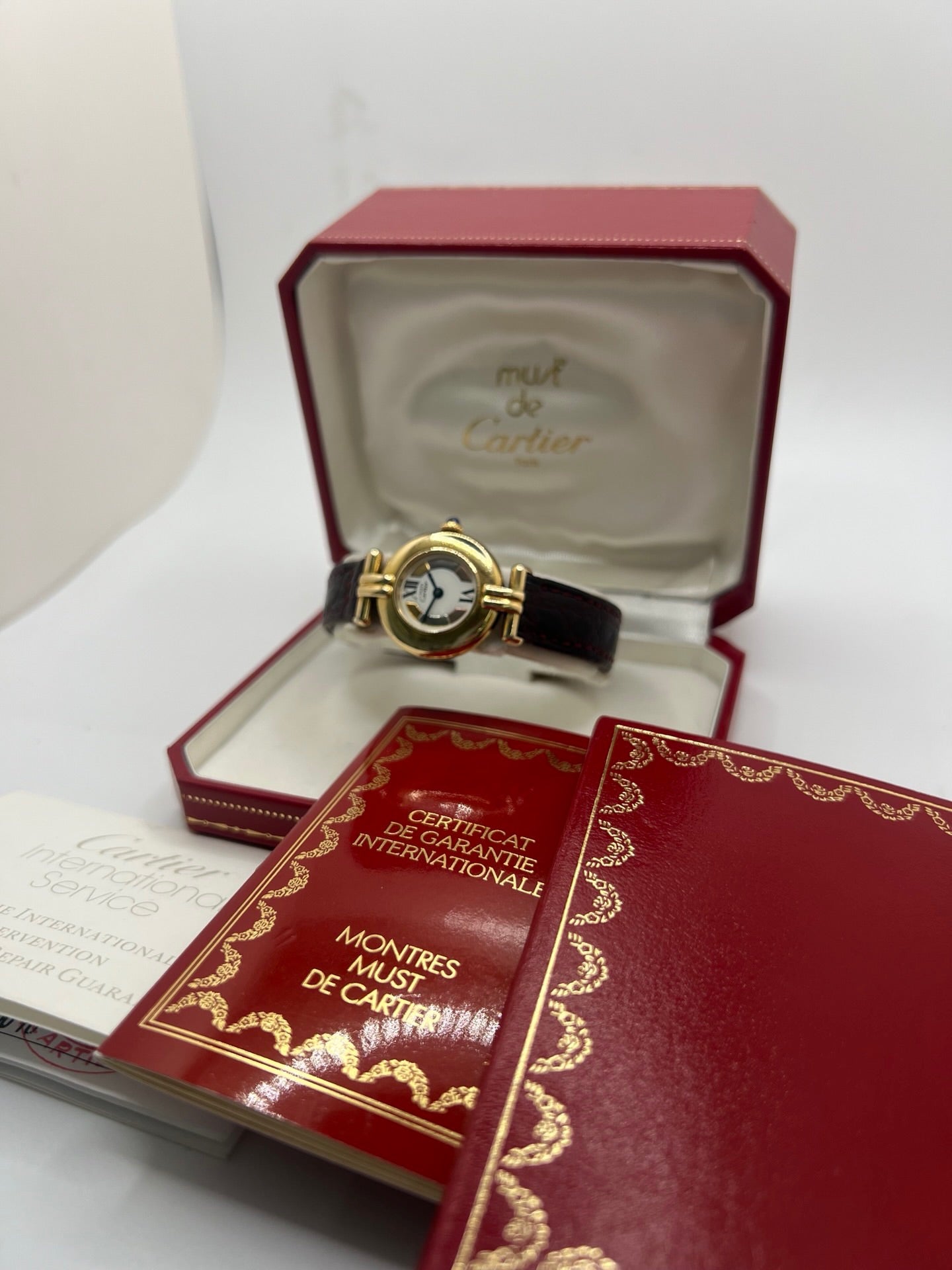 Montre femme Cartier Colisée réf. 590002 en argent avec mouvement quartz. Modèle vintage de 1995 au cadran blanc à chiffres romains et bracelet en cuir or. Verre saphir, boucle ardillon en argent. Élégance intemporelle signée Cartier, livrée avec coffret et papiers d’origine. Montre d’occasion en bon état, révisée en 2025.