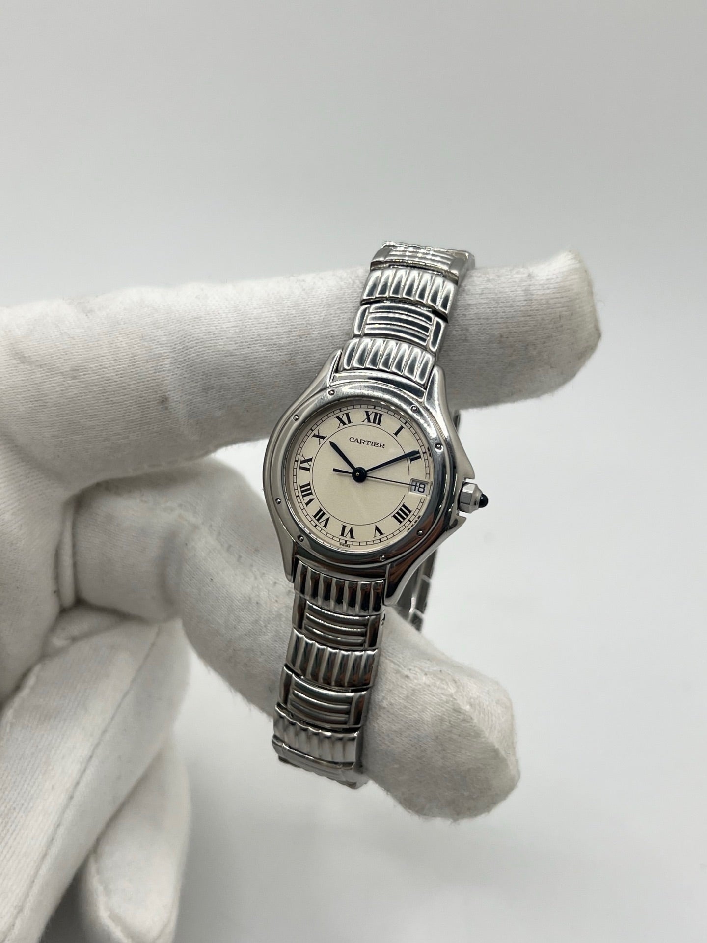 Montre Cartier Cougar référence 1215 1 en acier inoxydable avec boîtier de 26 mm et bracelet assorti. Ce modèle à mouvement quartz se distingue par son cadran blanc à chiffres romains, son verre saphir résistant aux rayures et son affichage de la date. Son design emblématique allie élégance et sobriété, caractéristique des créations horlogères de la maison Cartier. Montre d'occasion de 1995 en très bon état, révisée, avec coffret et papiers d'origine.
