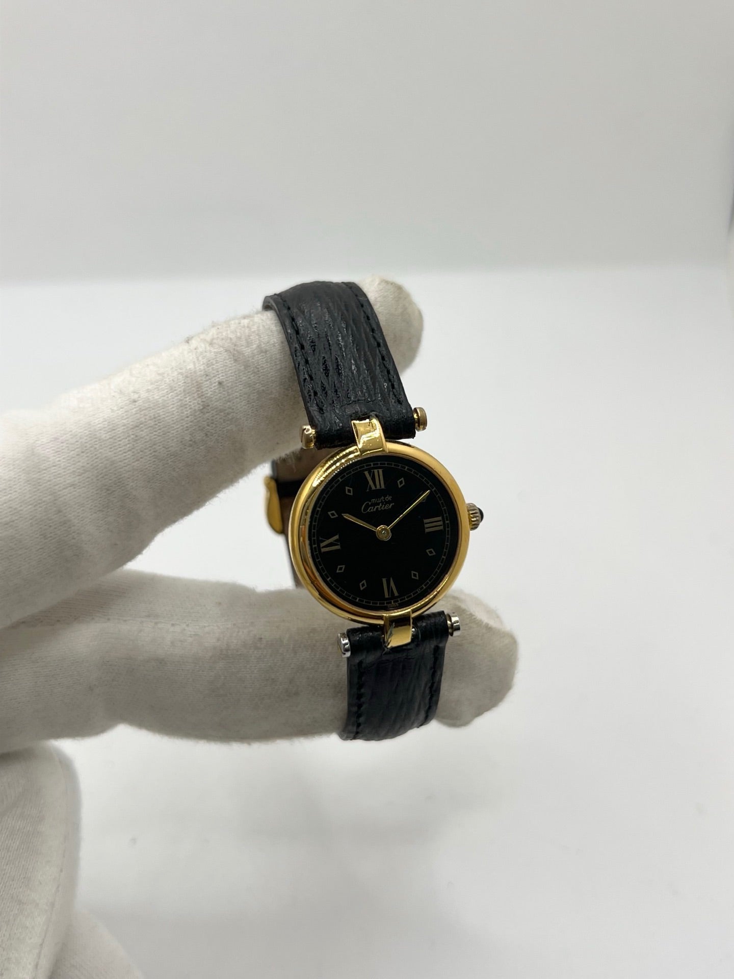 Cartier Must Vendôme référence 590004 en argent avec boîtier de 24 mm, cadran noir à chiffres romains et mouvement à quartz. Cette montre femme est équipée d'un bracelet en cuir, d'une boucle ardillon en acier et d'un verre saphir. Modèle d'occasion en très bon état, révisé en interne en 2026. Une montre Cartier vintage au design élégant, idéale pour les amateurs d'horlogerie de luxe et de pièces intemporelles.
