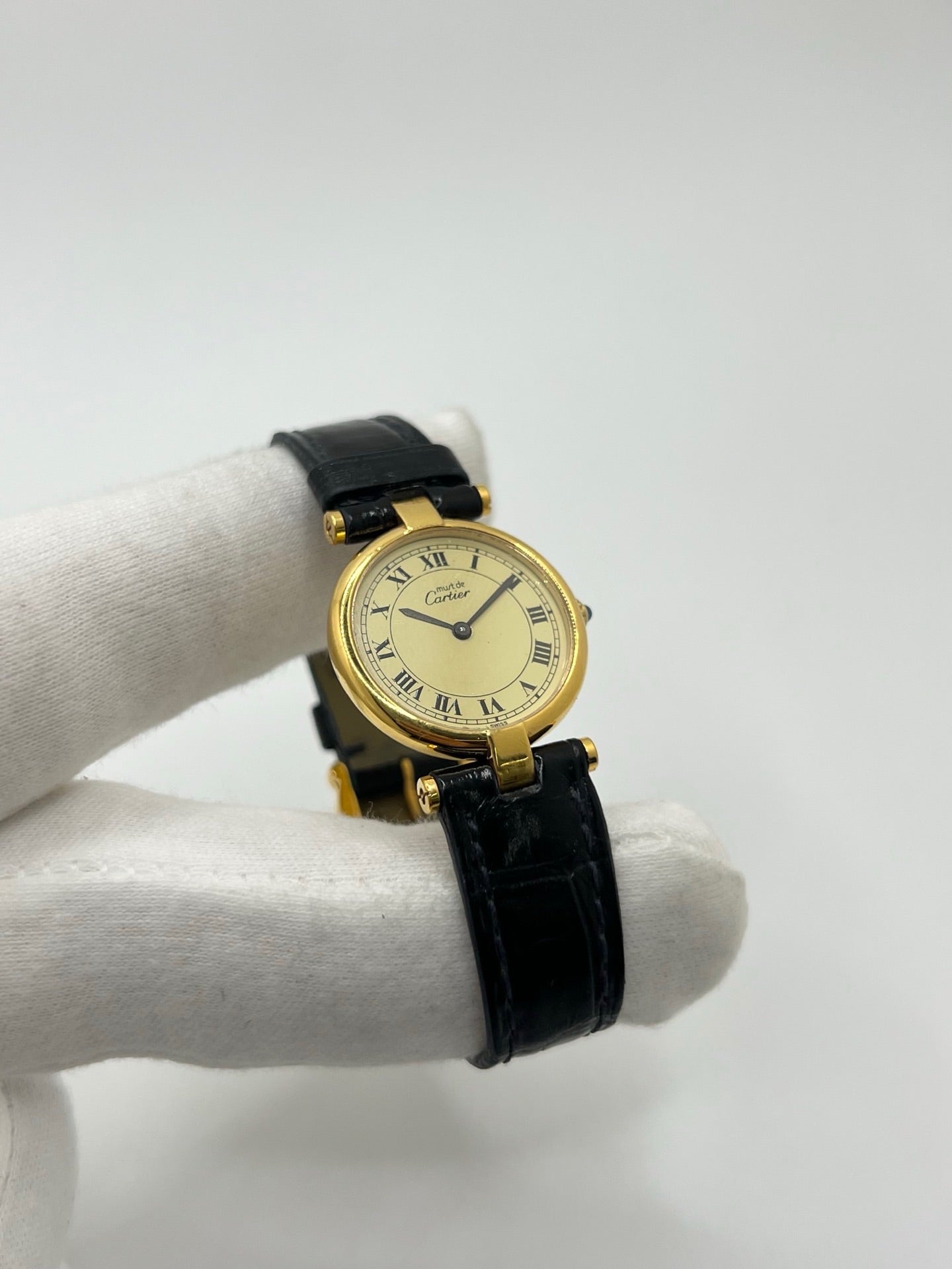 Montre Cartier Must Vendôme en vermeil, boîtier en argent plaqué or au diamètre de 30 mm, accompagnée d’un cadran blanc à chiffres romains signature. Équipée d’un mouvement quartz précis et d’un bracelet en cuir noir avec boucle en acier. Modèle élégant et intemporel, idéal pour un poignet féminin. Montre d’occasion en très bon état, présentant de légères micro-rayures, révisée en interne, livrée avec son coffret d’origine.