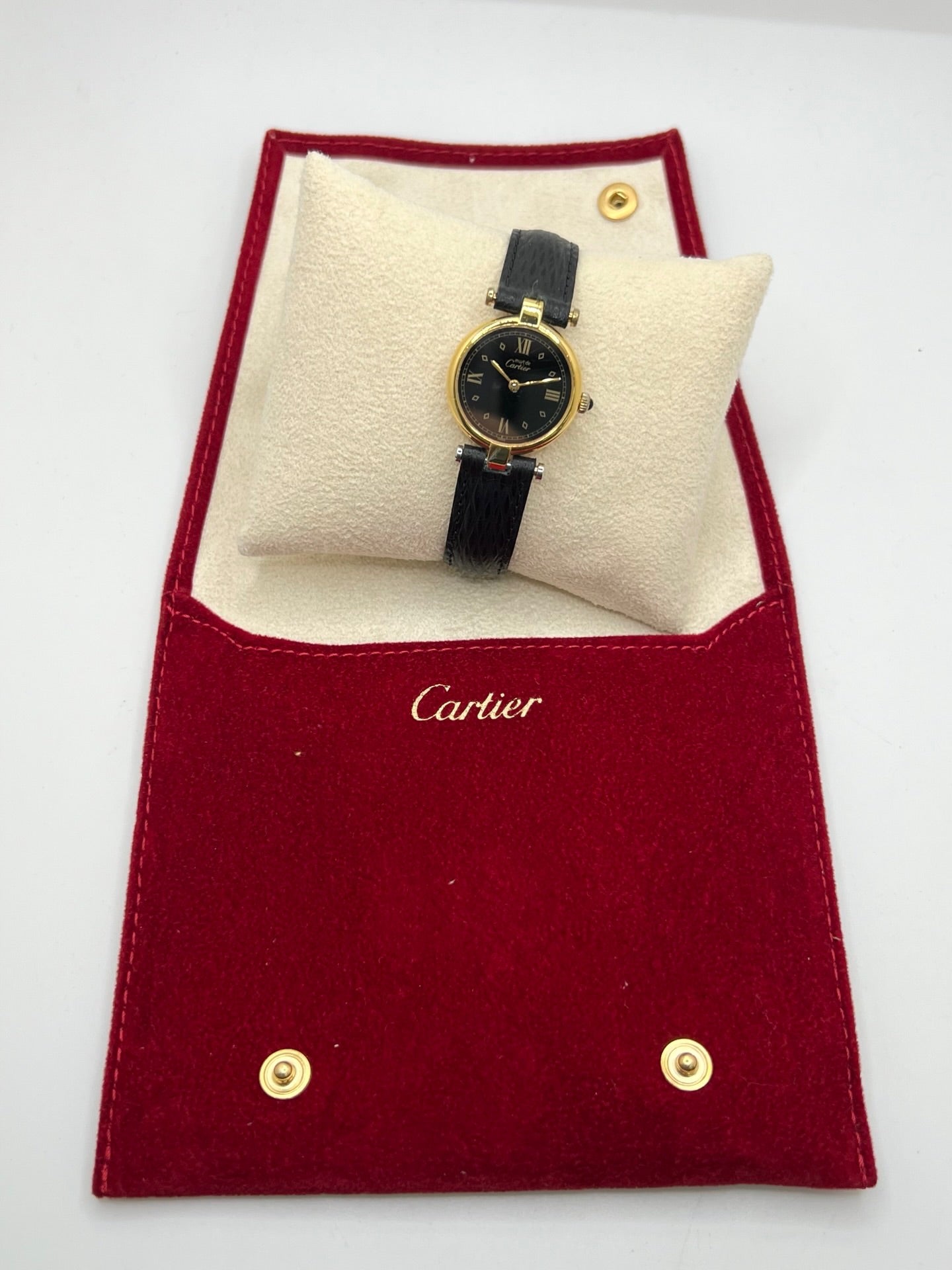 Cartier Must Vendôme référence 590004 en argent avec boîtier de 24 mm, cadran noir à chiffres romains et mouvement à quartz. Cette montre femme est équipée d'un bracelet en cuir, d'une boucle ardillon en acier et d'un verre saphir. Modèle d'occasion en très bon état, révisé en interne en 2026. Une montre Cartier vintage au design élégant, idéale pour les amateurs d'horlogerie de luxe et de pièces intemporelles.
