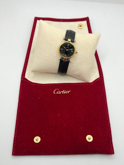 Cartier Must Vendôme référence 590004 en argent avec boîtier de 24 mm, cadran noir à chiffres romains et mouvement à quartz. Cette montre femme est équipée d'un bracelet en cuir, d'une boucle ardillon en acier et d'un verre saphir. Modèle d'occasion en très bon état, révisé en interne en 2026. Une montre Cartier vintage au design élégant, idéale pour les amateurs d'horlogerie de luxe et de pièces intemporelles.
