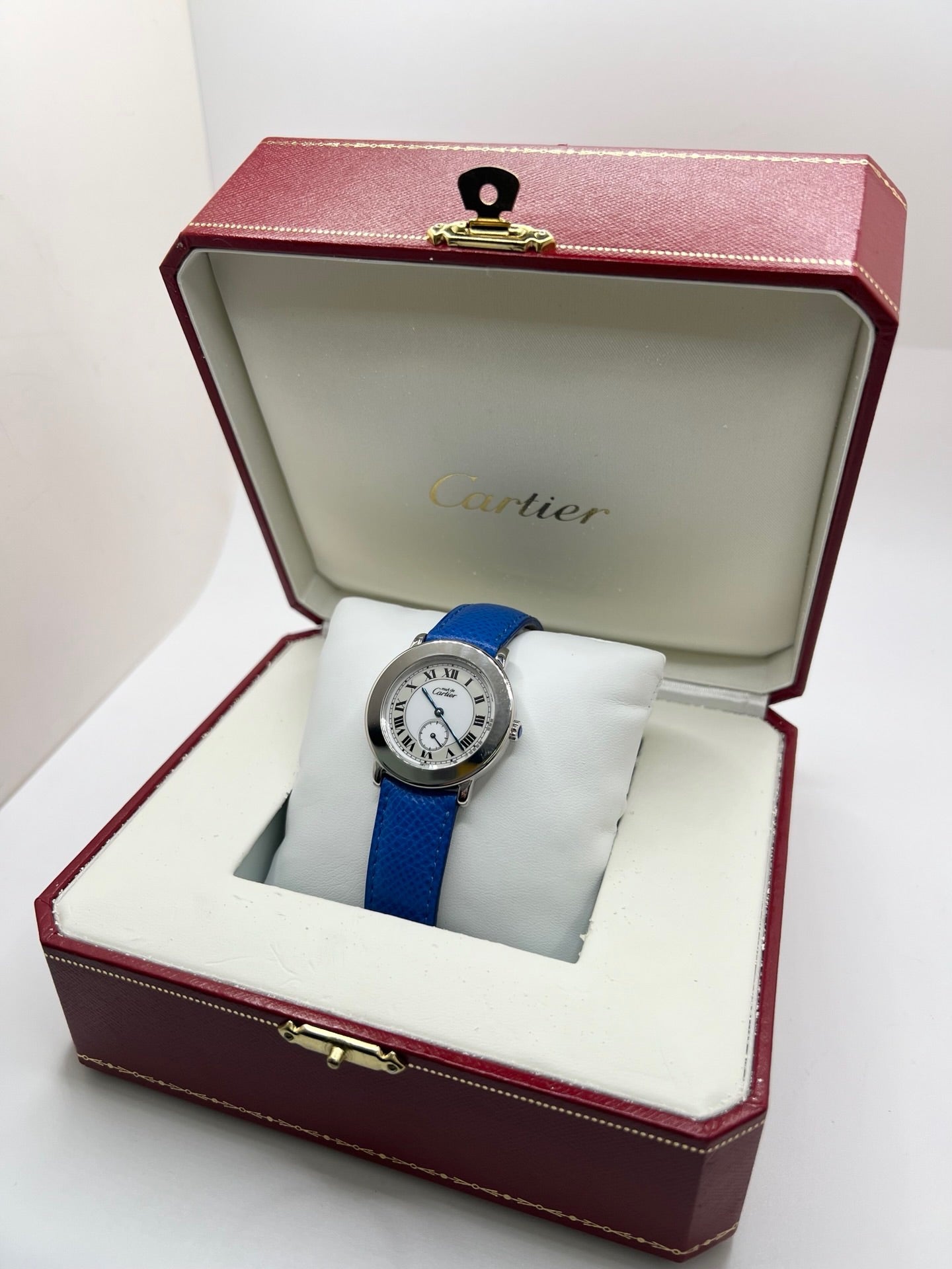 Montre Cartier Must de Cartier Ronde, modèle femme élégant à mouvement quartz. Boîtier rond en métal précieux, cadran blanc raffiné avec chiffres romains, design classique signature Cartier. Bracelet cuir bleu avec boucle ardillon en acier. Verre saphir résistant, diamètre 33 mm. Montre de luxe d’occasion en très bon état, avec légères traces d’usage peu visibles. Révisée en interne le 22 avril 2026. Livrée avec coffret d’origine, sans papiers, disponible à Paris.
