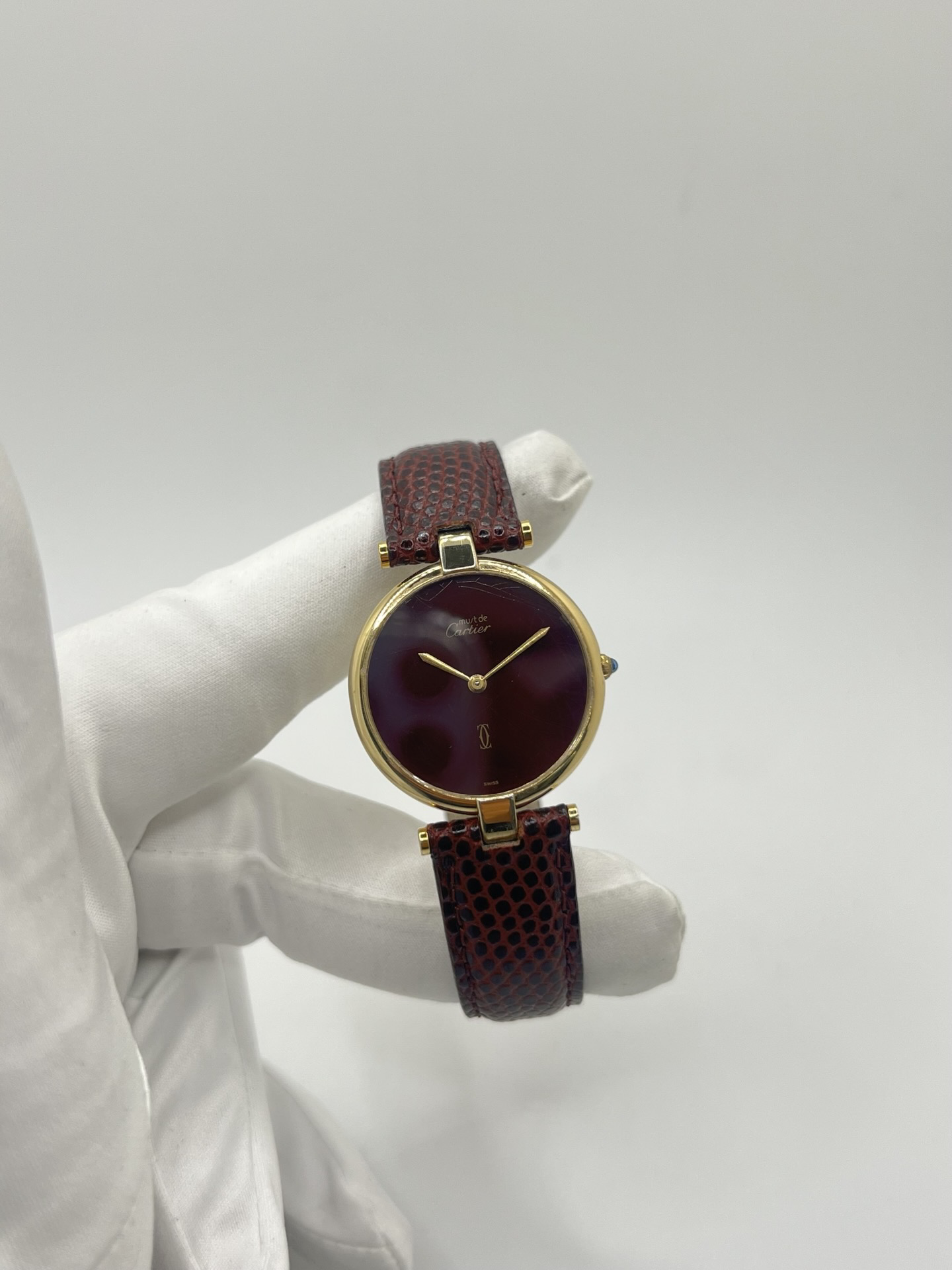 Montre Cartier Must Vendôme Vermeil 30 mm avec cadran bordeaux “burgundy”. Ce modèle vintage emblématique présente un boîtier rond en vermeil (argent plaqué or), un cadran laqué rouge profond signature de la collection Must, des aiguilles dorées élégantes et un design classique intemporel. Montre de luxe suisse recherchée par les collectionneurs, idéale pour les amateurs d’horlogerie vintage et de pièces iconiques au style raffiné.