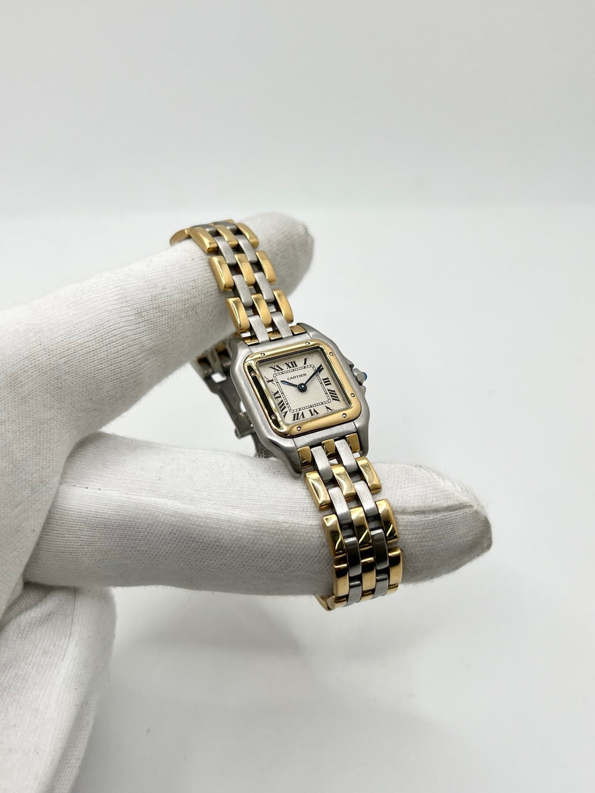 Montre Cartier Panthère 1057917 pour femme, modèle emblématique de la maison Cartier datant de 1989. Cette montre de luxe vintage associe élégamment l’or et l’acier, avec un cadran blanc raffiné, un verre saphir et un mouvement à quartz. La Cartier Panthère référence 1057917 est proposée d’occasion en très bon état, avec son coffret et ses papiers d’origine. Révisée en interne le 19 octobre 2026, cette montre Cartier Panthère en or et acier allie élégance intemporelle et savoir-faire horloger.
