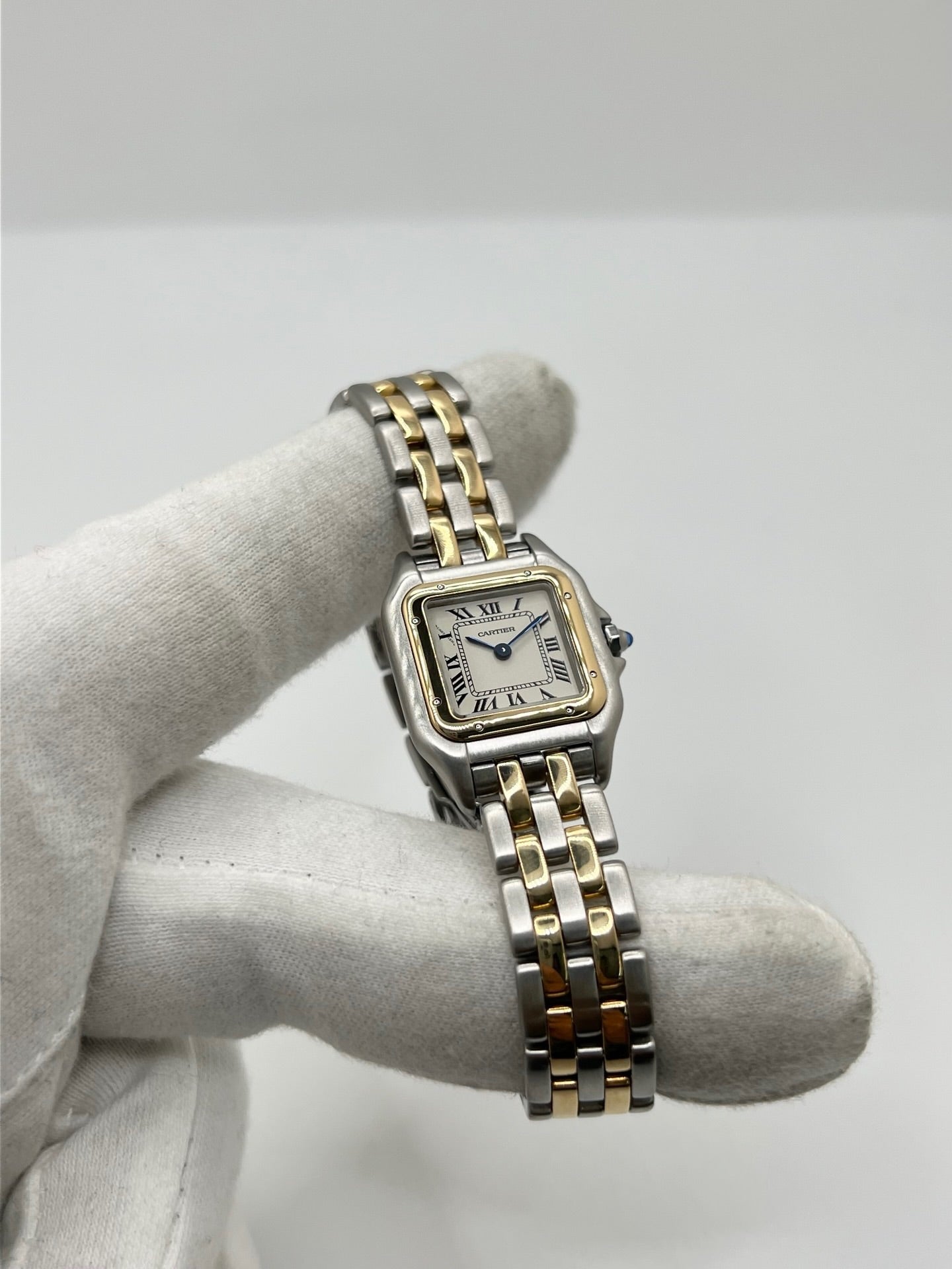 Montre Cartier Panthère référence 66921 pour femme en or jaune et acier, fabriquée en 1985 et équipée d'un mouvement quartz Swiss movement. Son boîtier rectangulaire de 22 x 30 mm est sublimé par une lunette en or jaune, un cadran blanc à chiffres romains et un verre saphir. Cette montre Cartier Panthère bicolore dispose d'un bracelet en or et acier avec boucle déployante. Vendue avec son coffret et ses papiers d'origine, elle est en très bon état et révisée en interne.