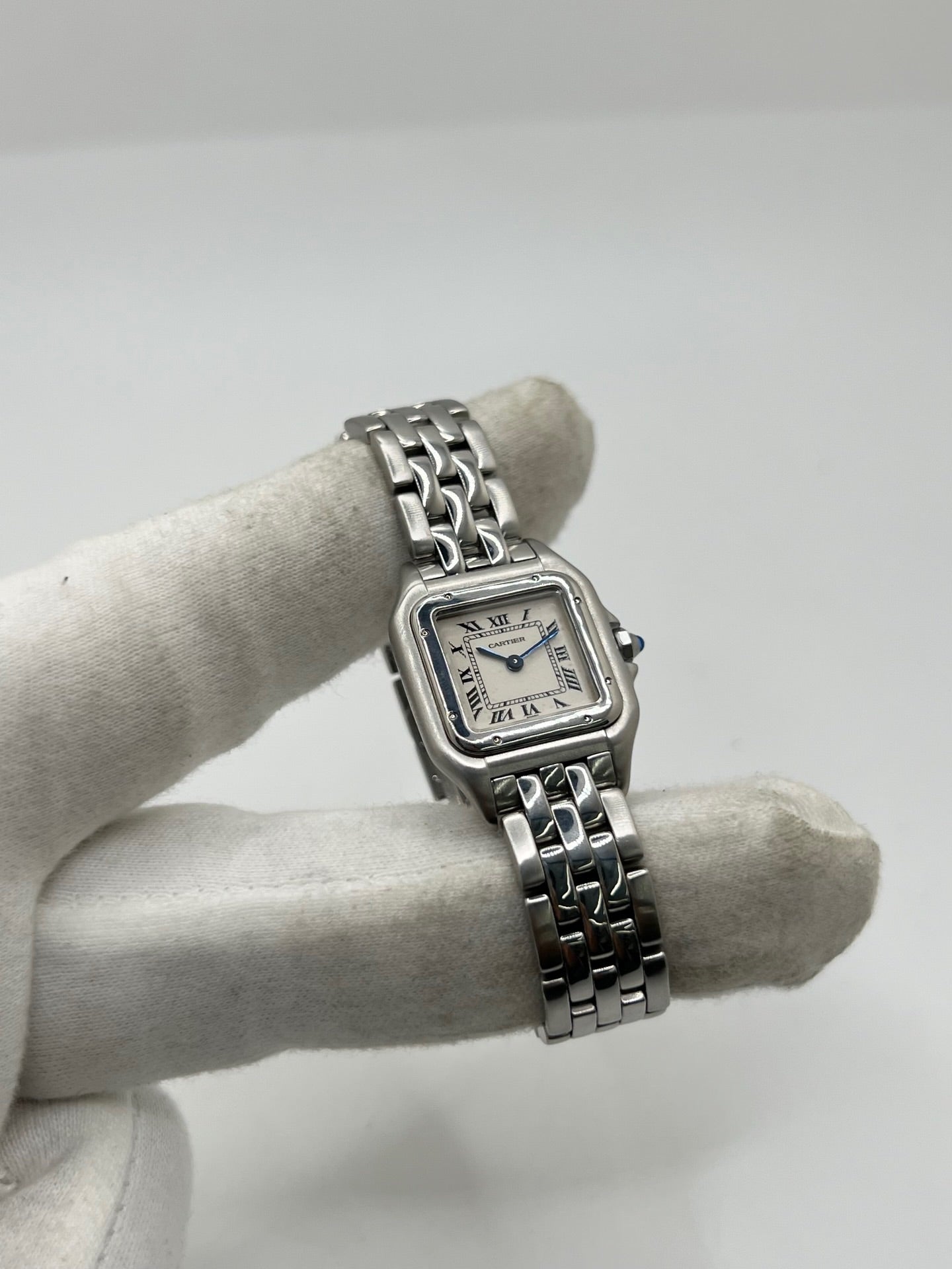 Cartier Panthère référence 1320 en acier avec boîtier de 22 mm, cadran blanc à chiffres romains et mouvement à quartz. Cette montre femme est équipée d'un bracelet en acier avec boucle déployante double pli et d'un verre saphir. Modèle d'occasion en très bon état, révisé par le fabricant en 2026, livré avec son coffret et ses papiers d'origine.