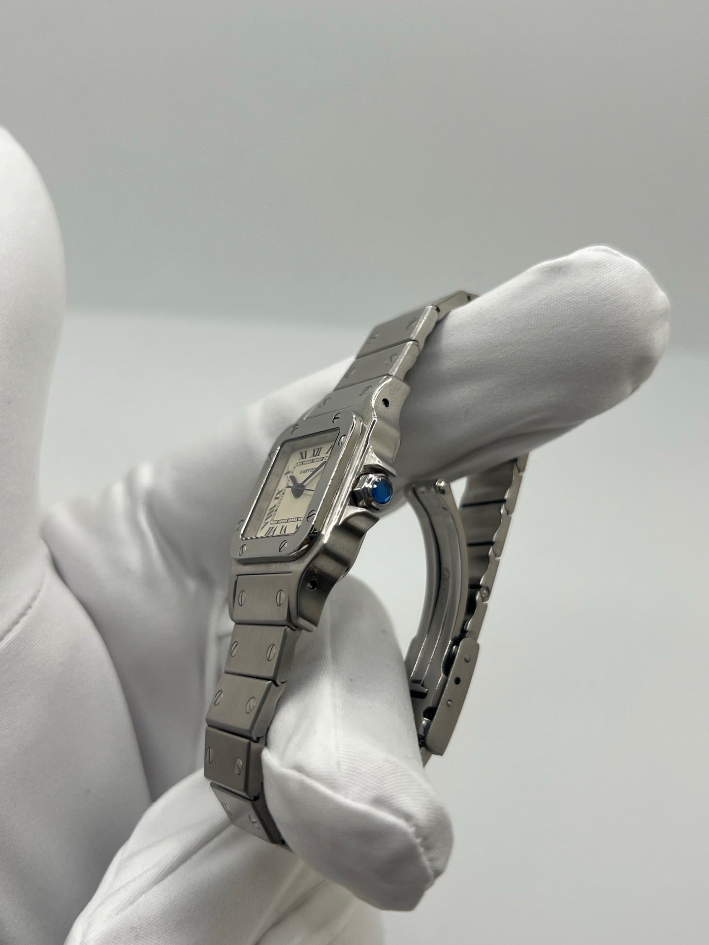 Montre Cartier Santos Lady en acier pour femme, modèle vintage à remontage automatique avec cadran blanc à chiffres romains, boîtier rectangulaire 24 x 35 mm, verre saphir et bracelet acier. Cette montre d’occasion en très bon état présente de légères traces d’usure discrètes. Livrée avec son coffret d’origine, sans papiers, cette Cartier Santos Lady allie élégance intemporelle, raffinement horloger et style iconique pour une collection de montres de luxe femme.