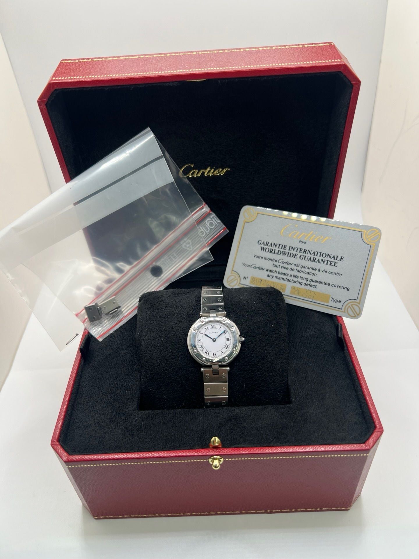 Montre Cartier Santos Vendôme référence 8192 en acier, modèle pour femme avec boîtier rond de 27 mm, cadran blanc à chiffres romains et mouvement quartz. Bracelet acier assorti, boucle à plis et verre saphir. Montre vintage de 1981 en très bon état, livrée avec coffret et papiers d’origine.