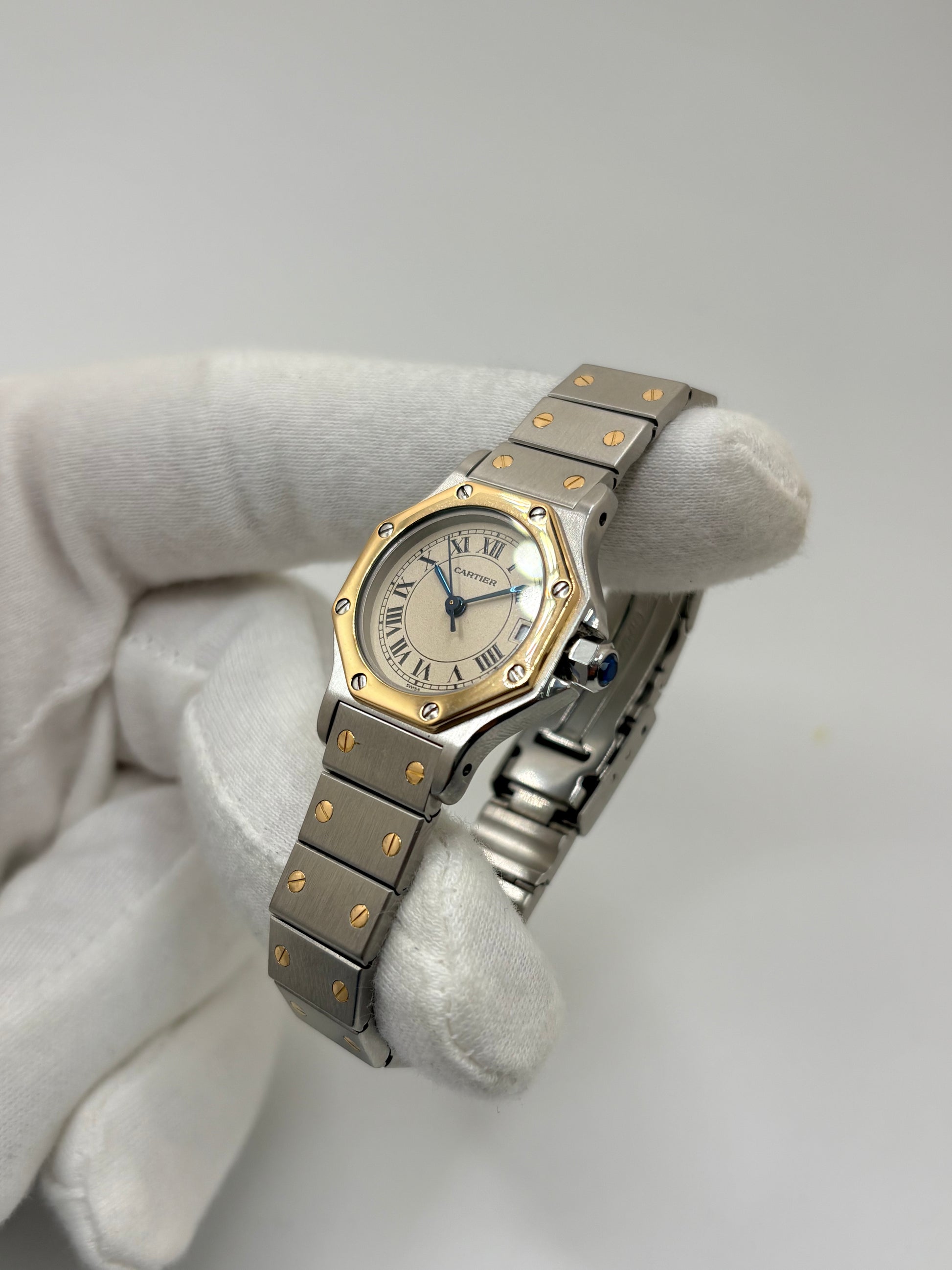 Montre Cartier Santos référence 187903 en or et acier avec boîtier de 24 x 31 mm, d'année inconnue et animée par un mouvement à quartz d'exception comptant 7 pierres. Son cadran blanc avec dateur est protégé par un verre saphir et complété par un bracelet en or et acier avec boucle pliante. Cette montre Cartier pour femme d'occasion est en très bon état, révisée en interne et livrée avec son coffret d'origine. Une pièce de luxe iconique disponible à Paris.