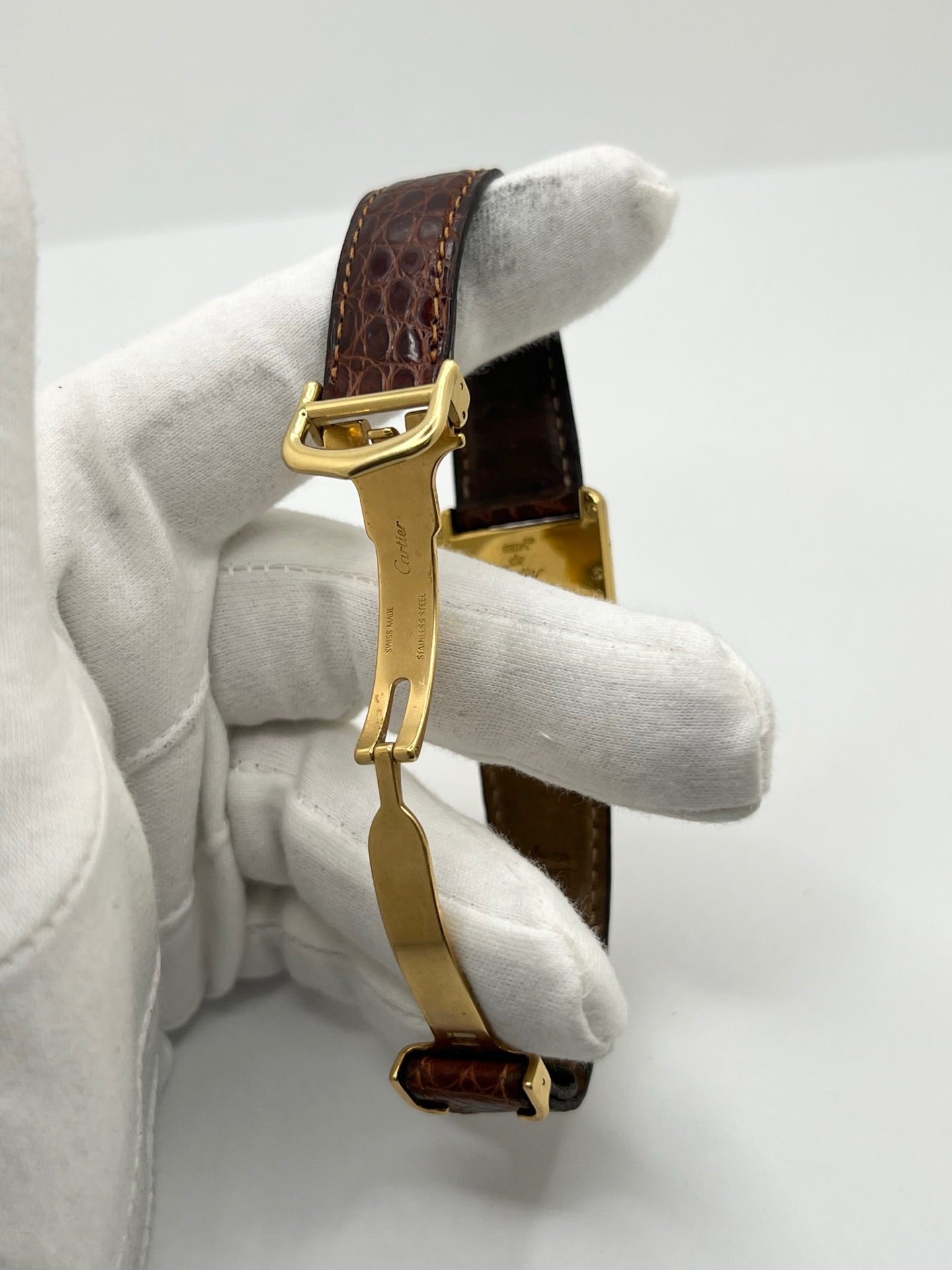Montre Cartier Tank Must grand modèle en argent avec cadran blanc à chiffres romains, mouvement quartz et fonction date. Boîtier rectangulaire 25 x 33 mm avec verre minéral, bracelet en cuir brun et boucle ardillon en acier. Modèle iconique au design élégant et intemporel, idéal pour homme ou unisexe. Montre d’occasion en bon état, révisée, avec coffret d’origine.