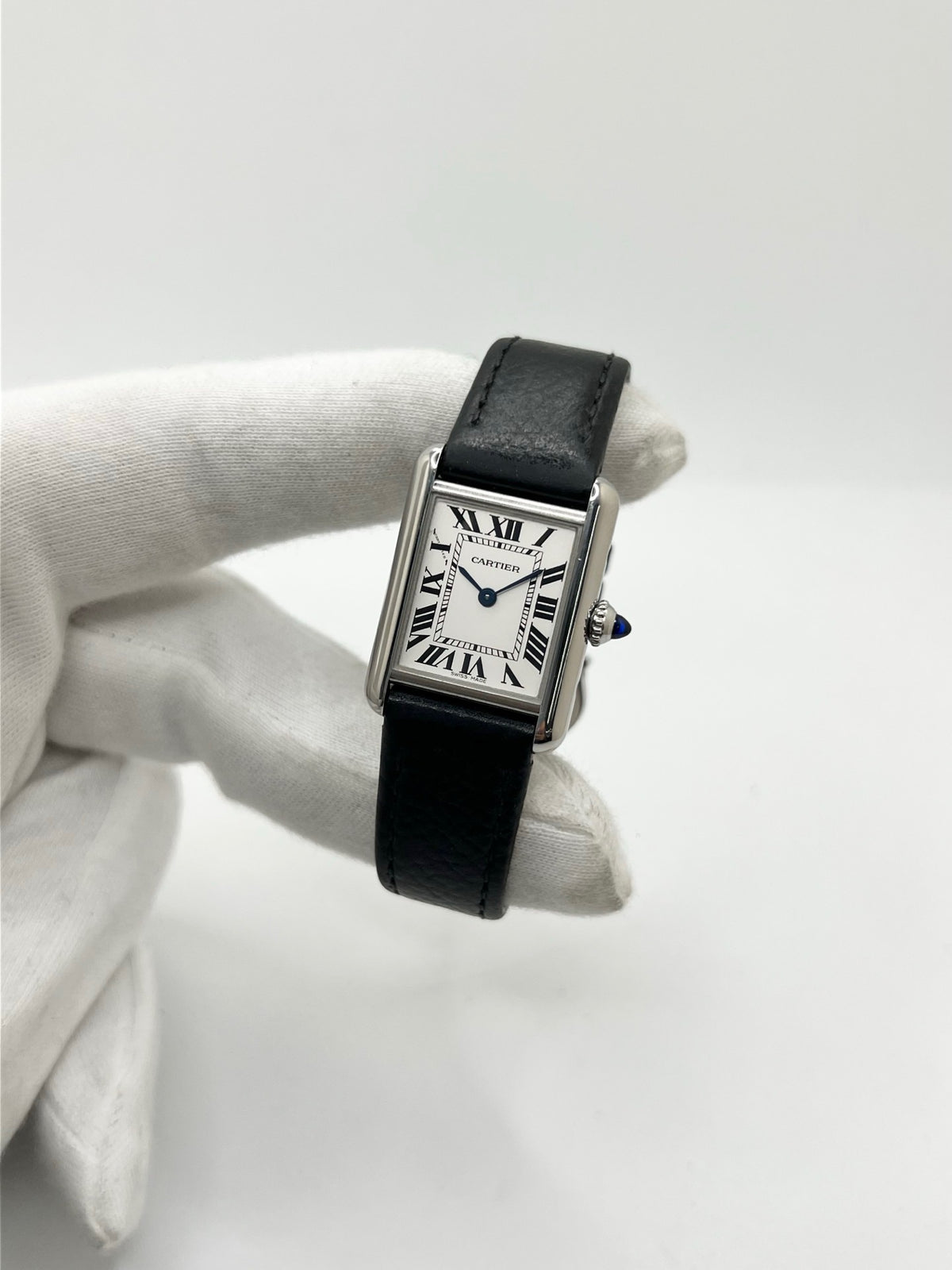 Montre Cartier Tank Must PM WSTA0042 pour femme, modèle élégant de la collection Tank datant de 2021. Cette montre de luxe se distingue par son boîtier rectangulaire en acier de 22 x 29 mm, son cadran argenté, son verre saphir et son bracelet en cuir noir. Équipée d’un mouvement à quartz, la Cartier Tank Must PM allie sobriété et élégance intemporelle. Proposée d’occasion en très bon état, elle est vendue avec son coffret d’origine et a bénéficié d’une révision interne le 19 octobre 2026.