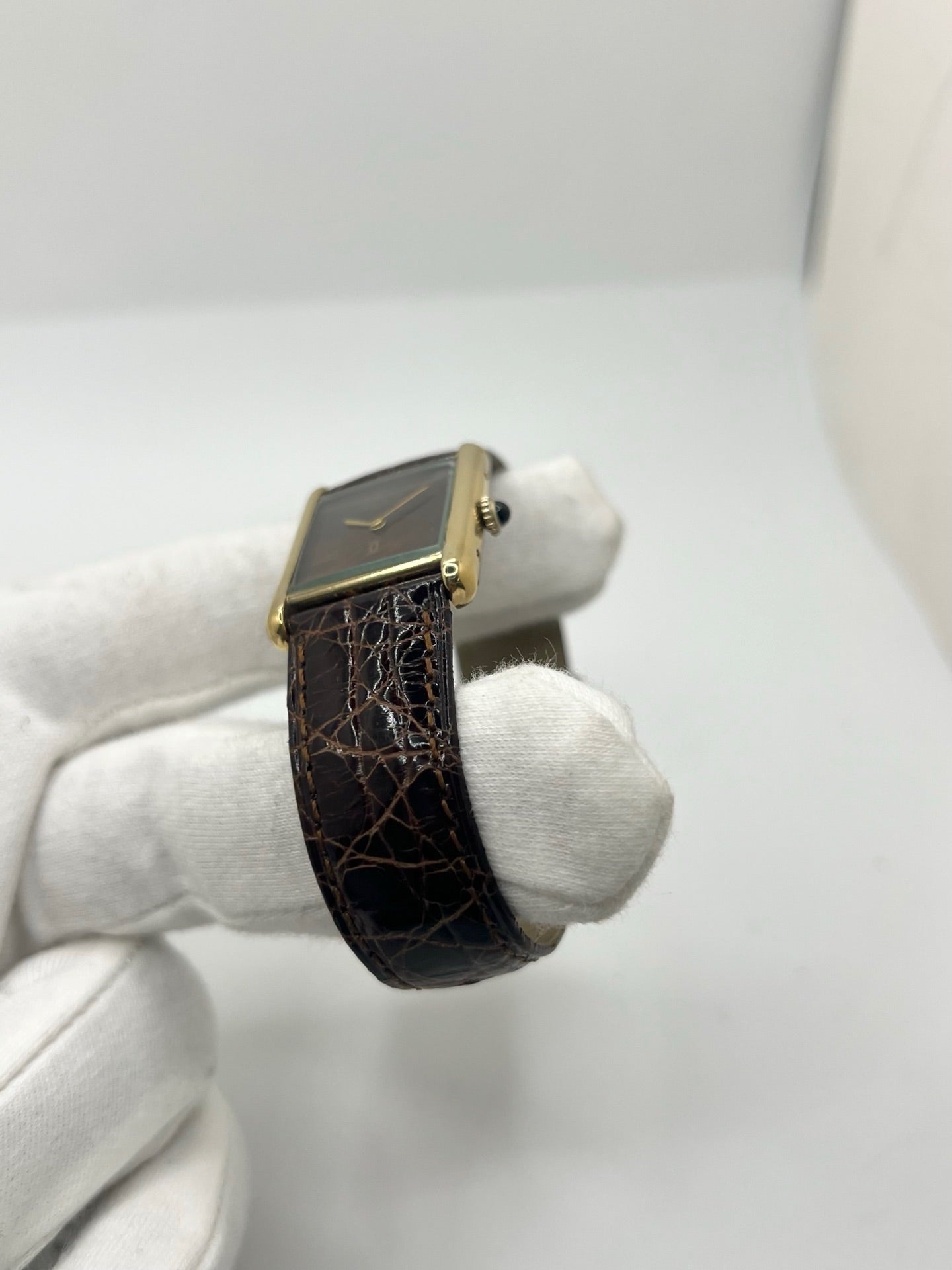 Montre Cartier Tank Must Vermeil Œil de Tigre vintage avec boîtier rectangulaire en vermeil, mouvement à remontage manuel et cadran en pierre naturelle œil de tigre aux reflets bruns et dorés. Cette Cartier Must Tank Vermeil se distingue par son design emblématique, son bracelet en cuir brun et son élégance intemporelle. Montre de collection recherchée par les amateurs de montres Cartier vintage, alliant raffinement, caractère et savoir-faire horloger.