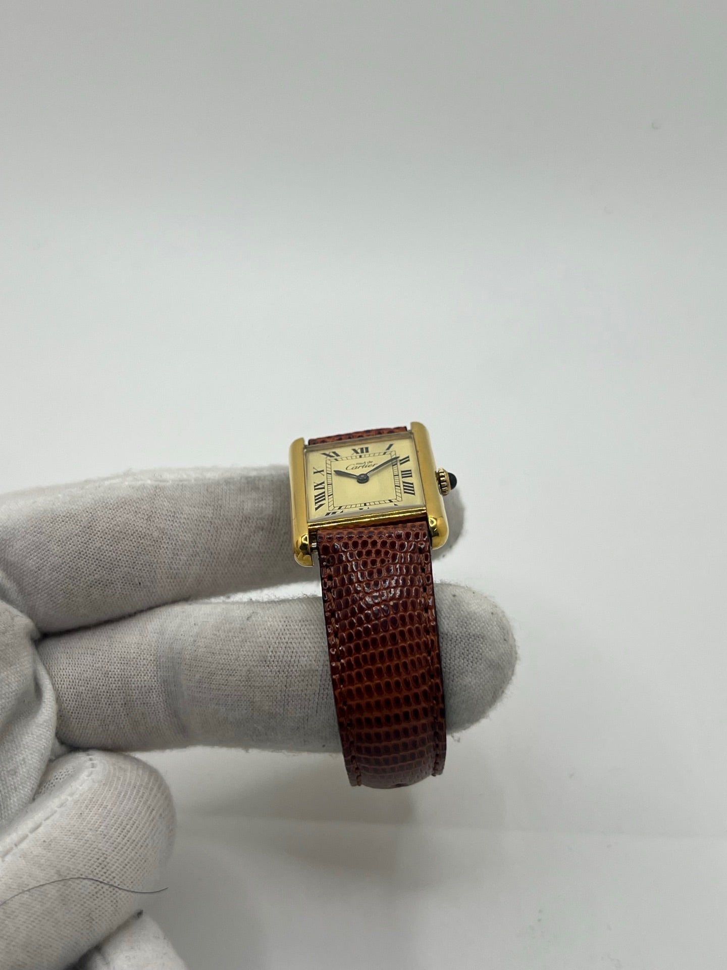 Montre Cartier Tank Must Vermeil, boîtier argent 31 x 23 mm, mouvement à remontage manuel Cartier 78-1 avec réserve de marche de 44 h et 17 pierres. Cadran blanc à chiffres romains, verre minéral. Bracelet en cuir de lézard brun avec boucle en argent. État d’occasion très bon avec légères rayures, alliant élégance intemporelle et design iconique pour homme ou unisexe.