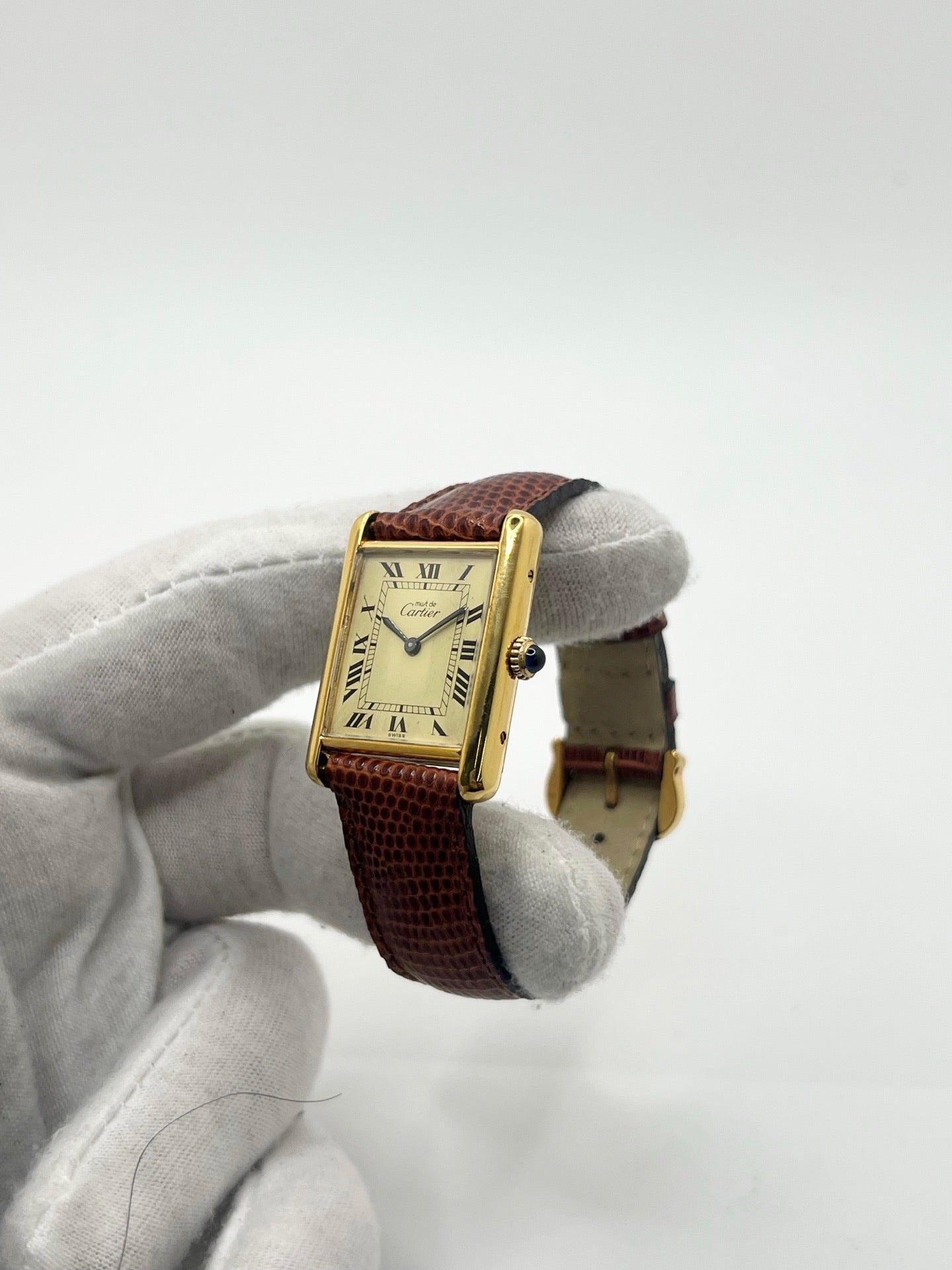 Montre Cartier Tank Must Vermeil, boîtier argent 31 x 23 mm, mouvement à remontage manuel Cartier 78-1 avec réserve de marche de 44 h et 17 pierres. Cadran blanc à chiffres romains, verre minéral. Bracelet en cuir de lézard brun avec boucle en argent. État d’occasion très bon avec légères rayures, alliant élégance intemporelle et design iconique pour homme ou unisexe.