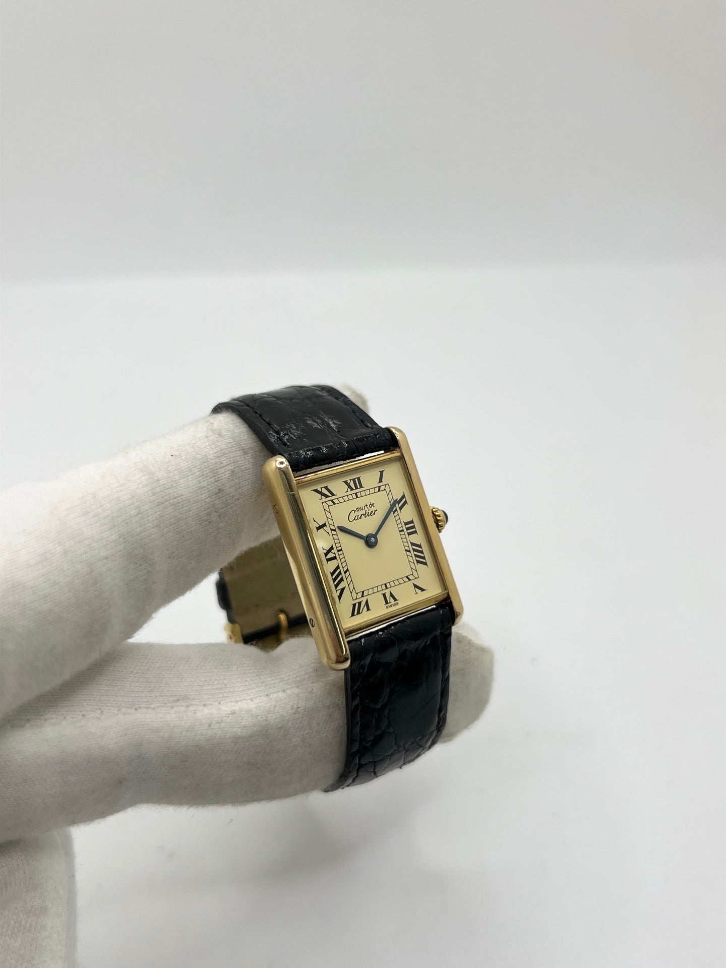 Montre Cartier Tank Vermeil réf. 590005 en argent avec mouvement à quartz, cadran champagne à chiffres romains et verre saphir. Ce modèle emblématique est monté sur un bracelet en cuir de crocodile noir avec boucle ardillon en acier. Son boîtier de 23 × 30 mm offre une élégance intemporelle. Cette montre Cartier Tank Vermeil d'occasion est en très bon état, révisée en interne et livrée avec son coffret d'origine.